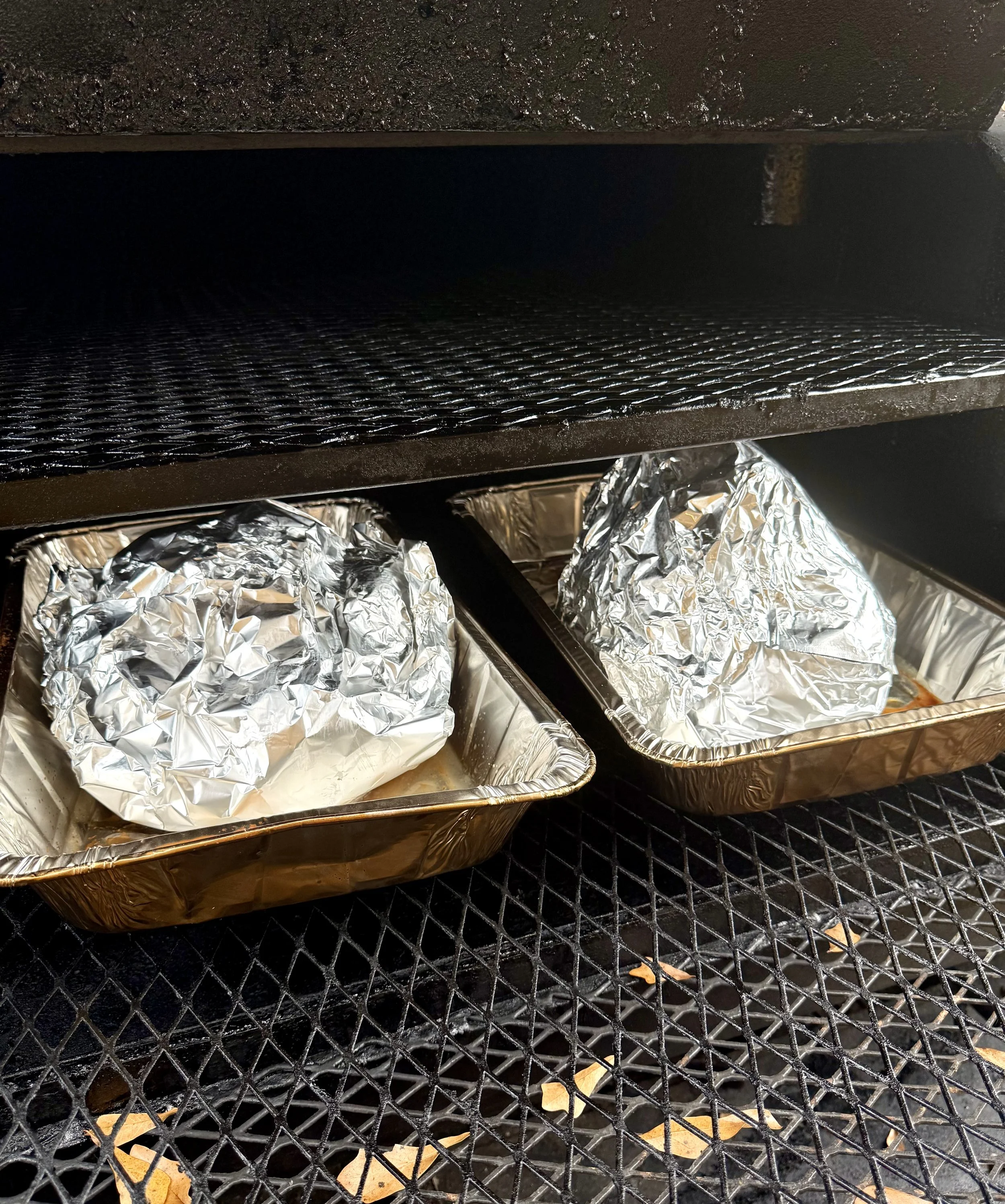 Whole turkeys wrapped in foil, ready to be smoked low and slow on a reverse-flow smoker with hickory wood smoke.