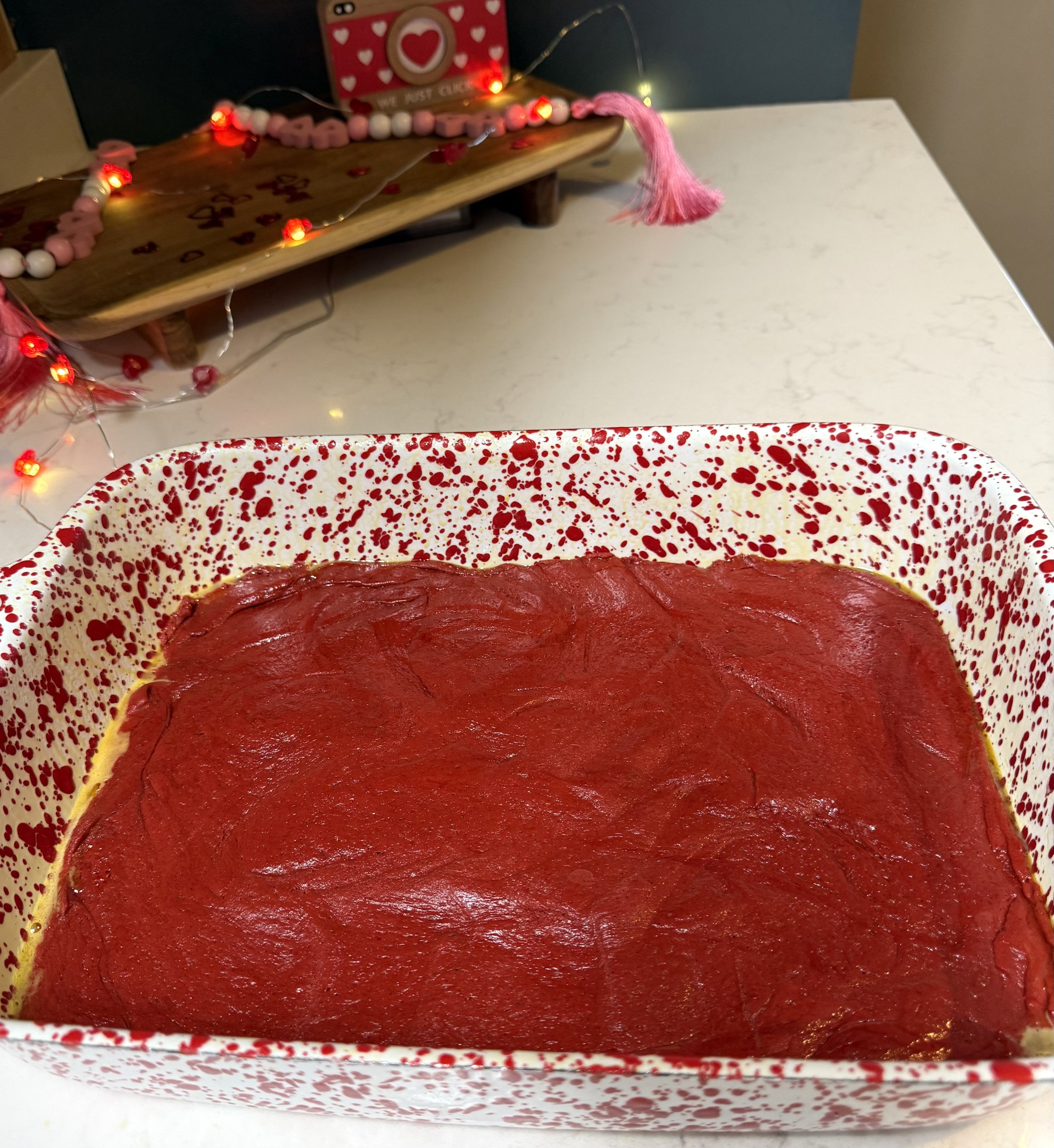 Red velvet cake mix base pressed into a 9X13 baking dish before adding a cream cheese layer for gooey butter cake bars.