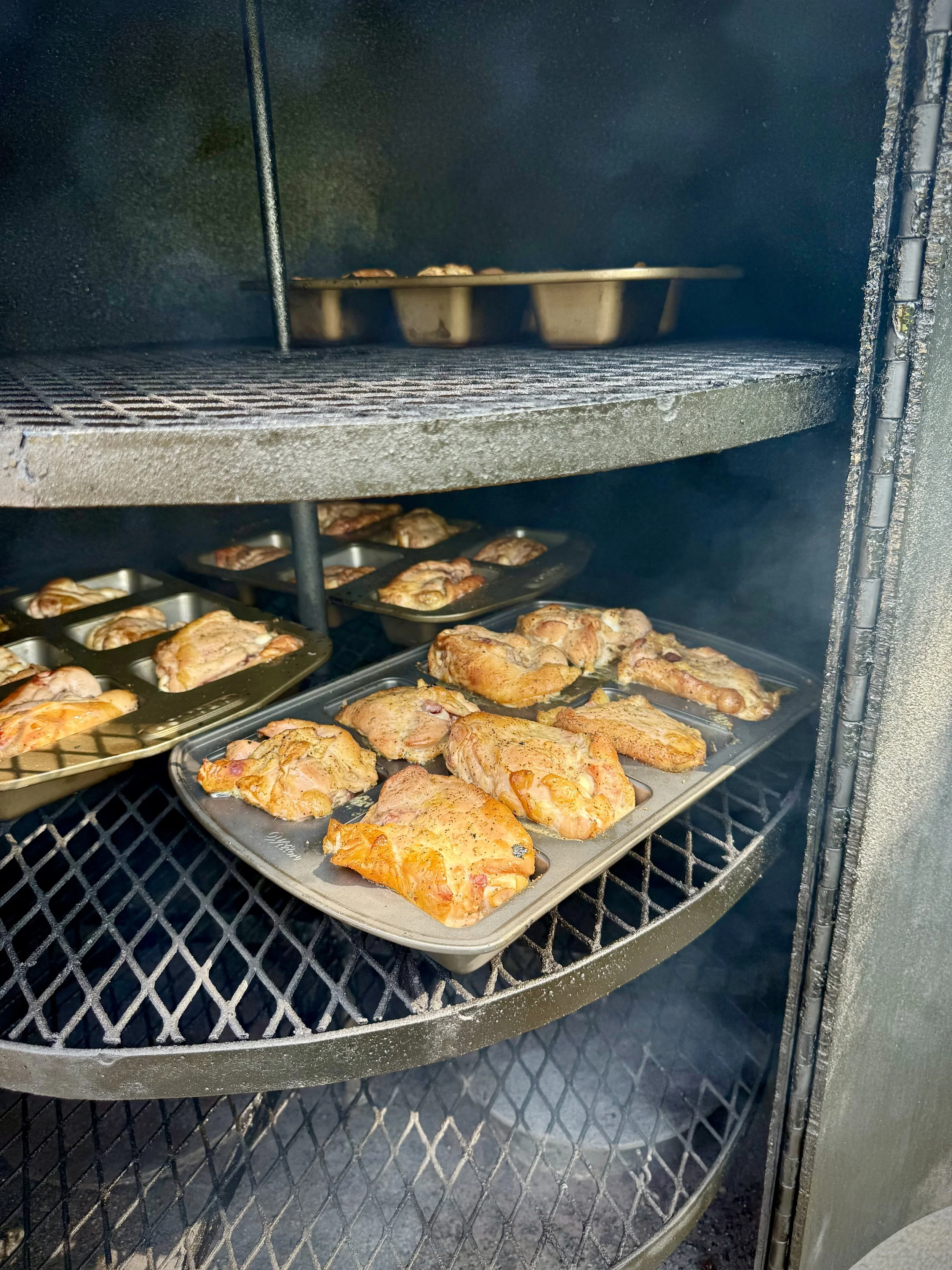 Smokey, mouth watering, fall apart tender BBQ chicken thighs on the rotisserie section of a reverse-flow home built smoker.