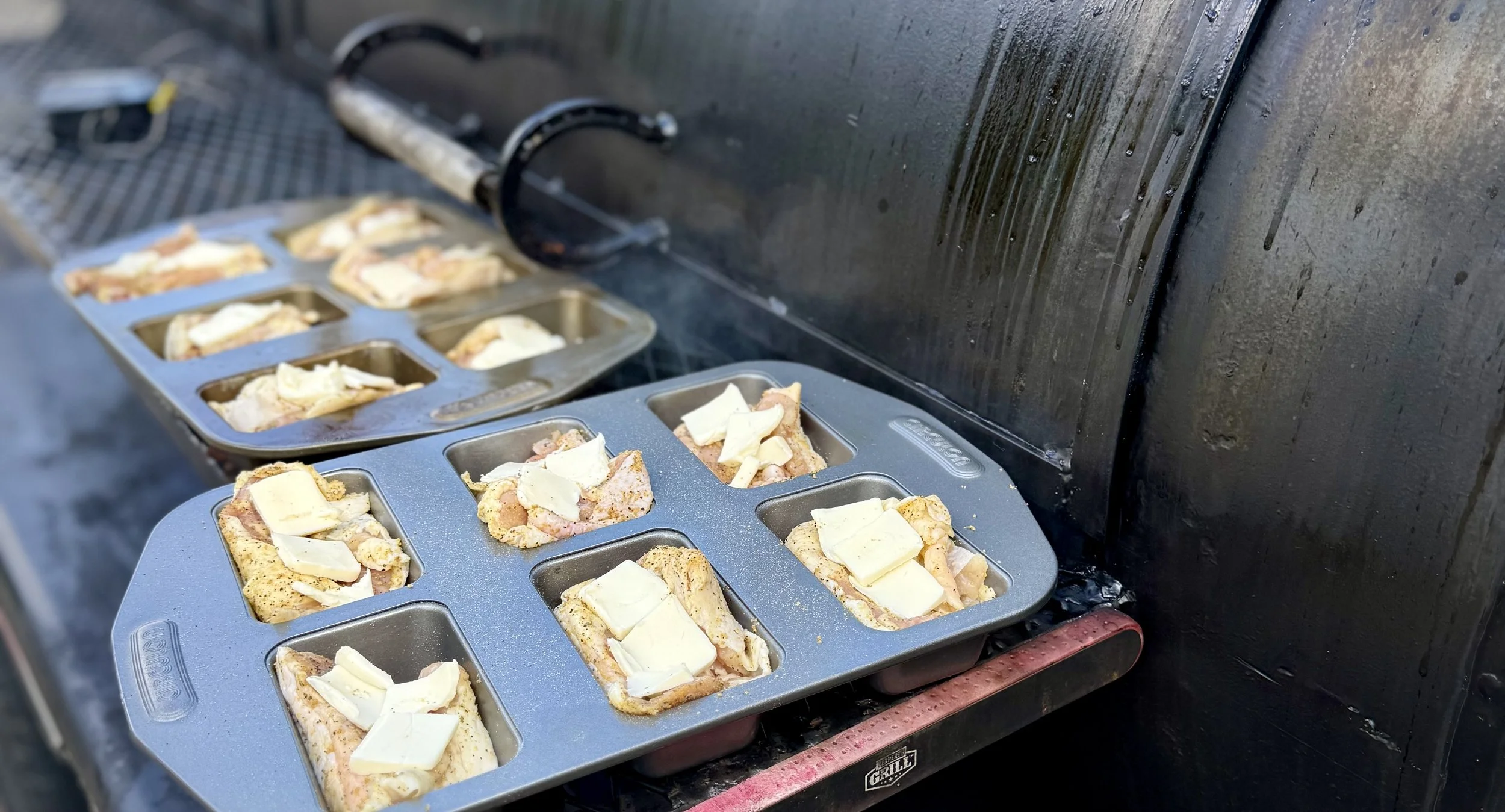 Competition chicken thighs ready to be smoked with a pat of butter right on top