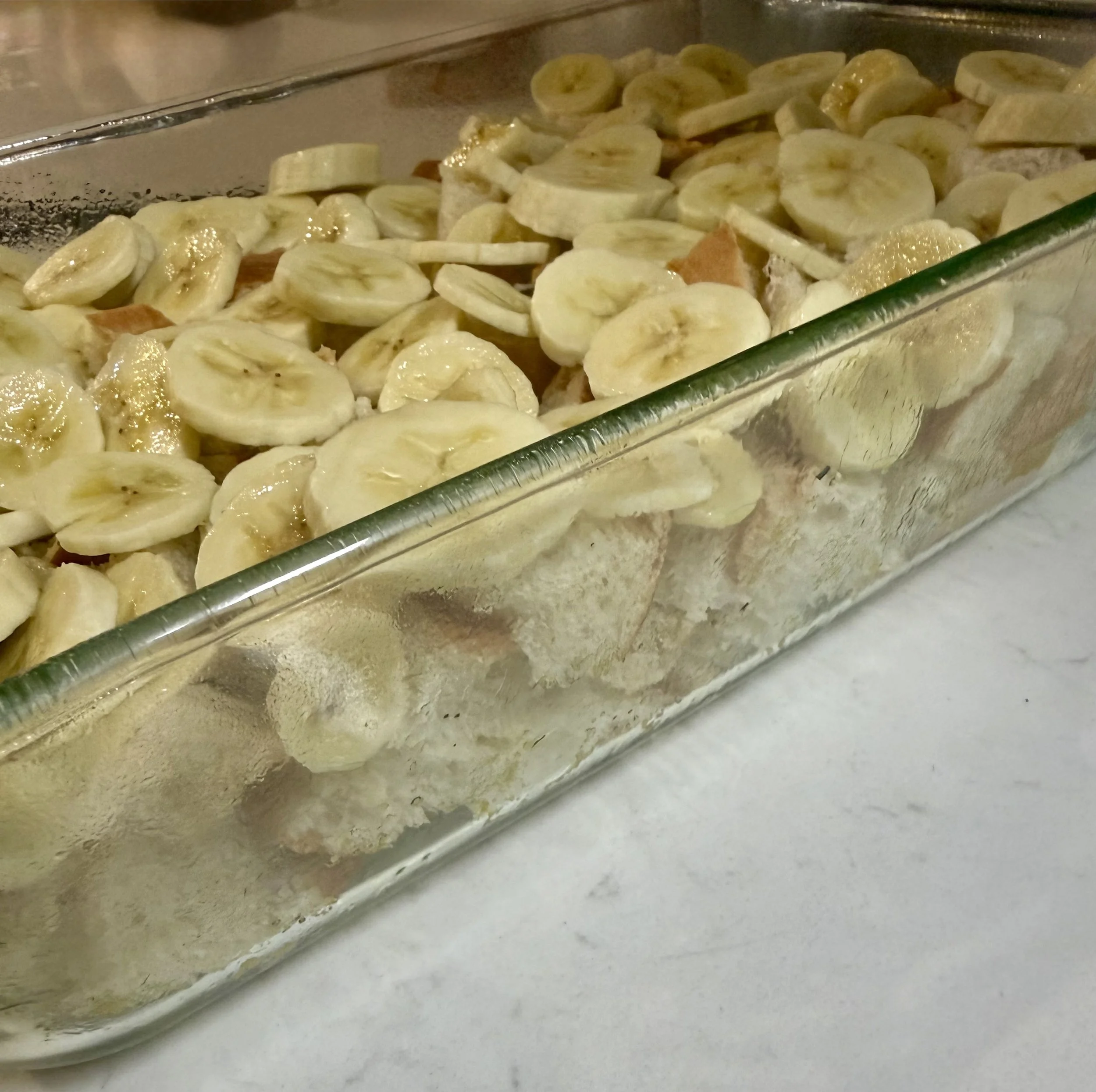 Bananas sliced on top of French bread chunks ready to soak up the custard mixture for the bananas foster bread pudding.