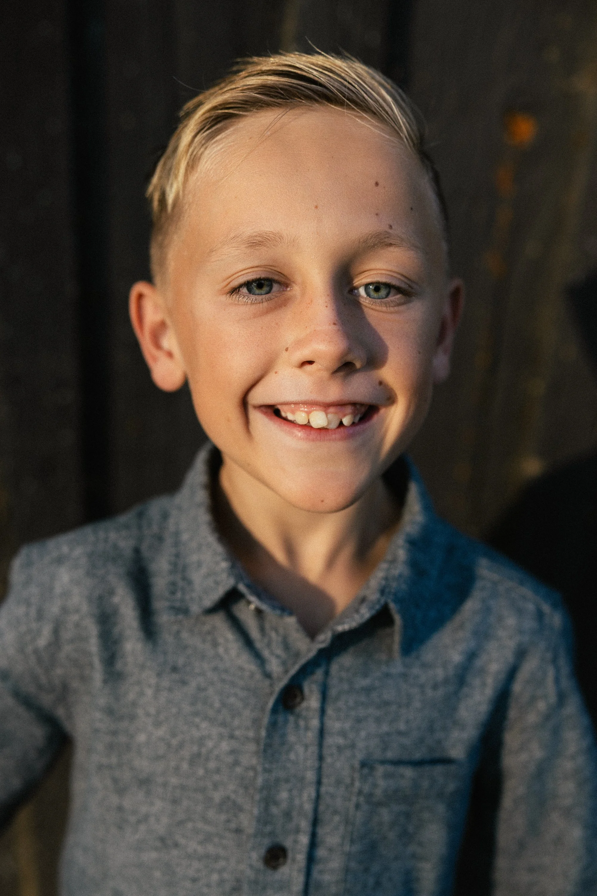 Close-up portrait of a young boy smiling in soft side light.