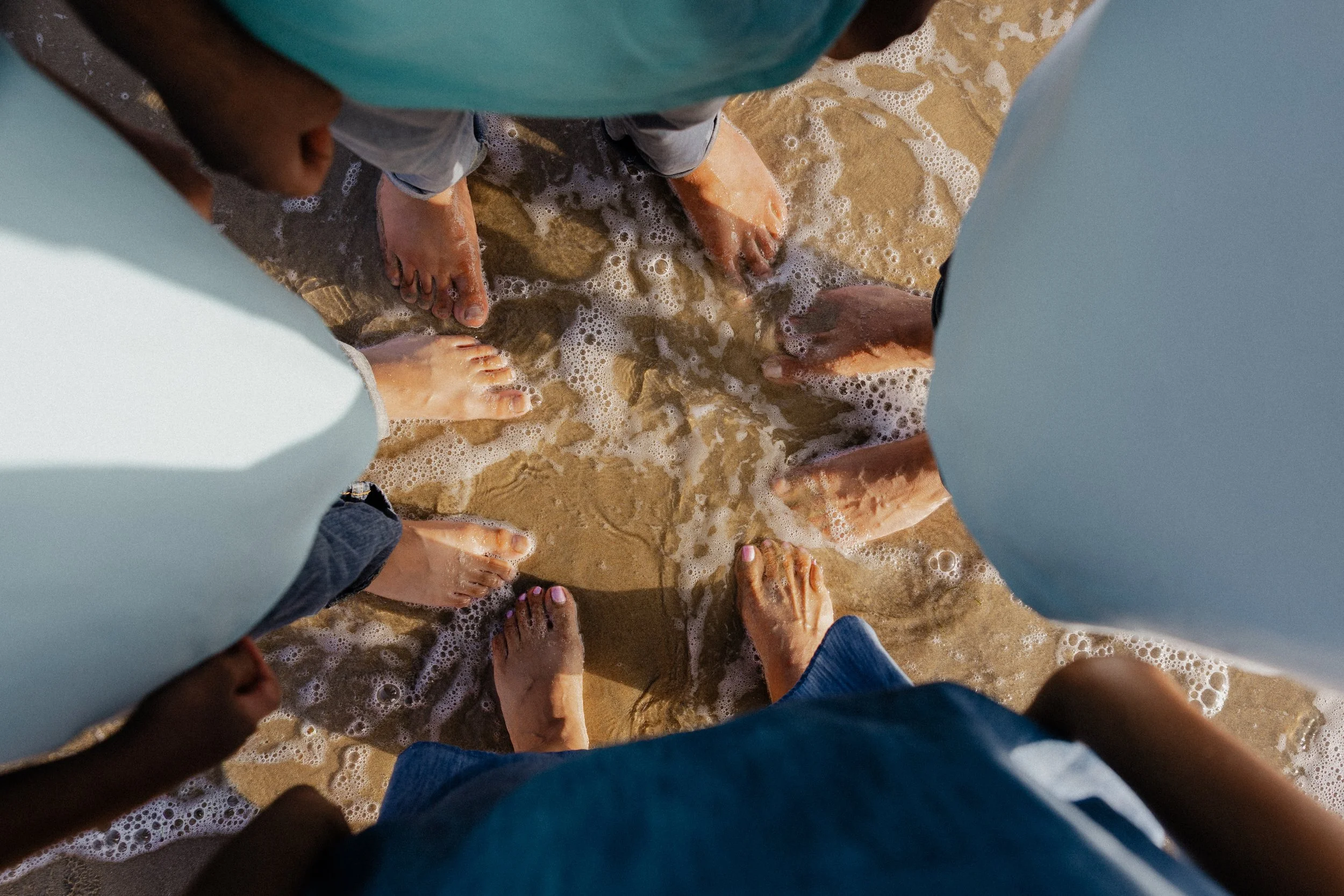 Close-up of family standing barefoot in the ocean waves at Crystal Cove State Park in Newport Beach.