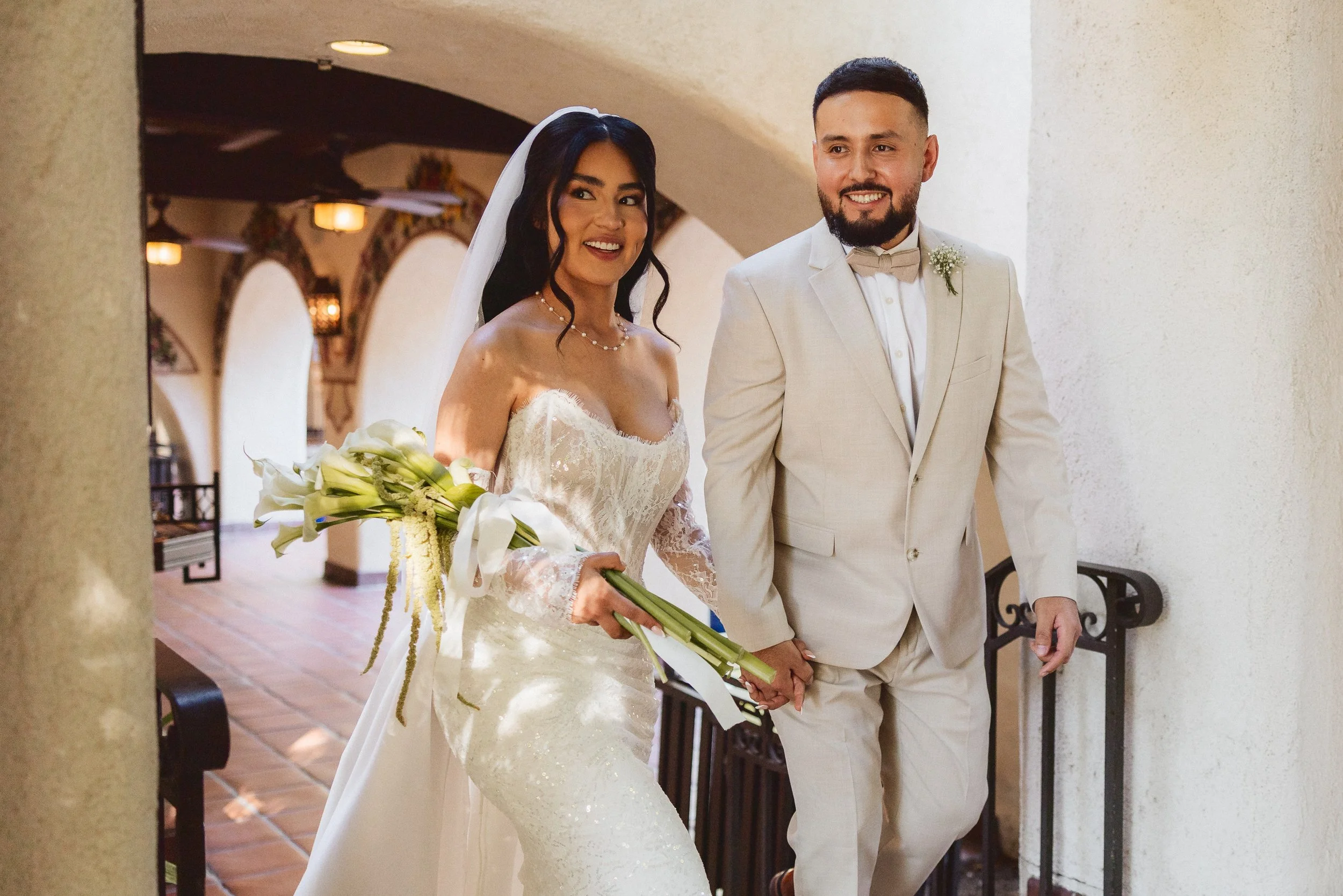 Bride and groom smiling while walking upstairs inside Los Angeles River Center and Gardens.