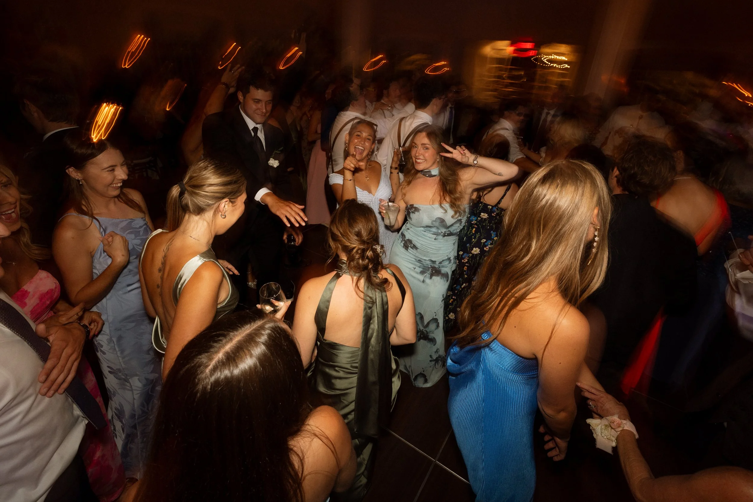 Guests fill the dance floor laughing and dancing at the reception