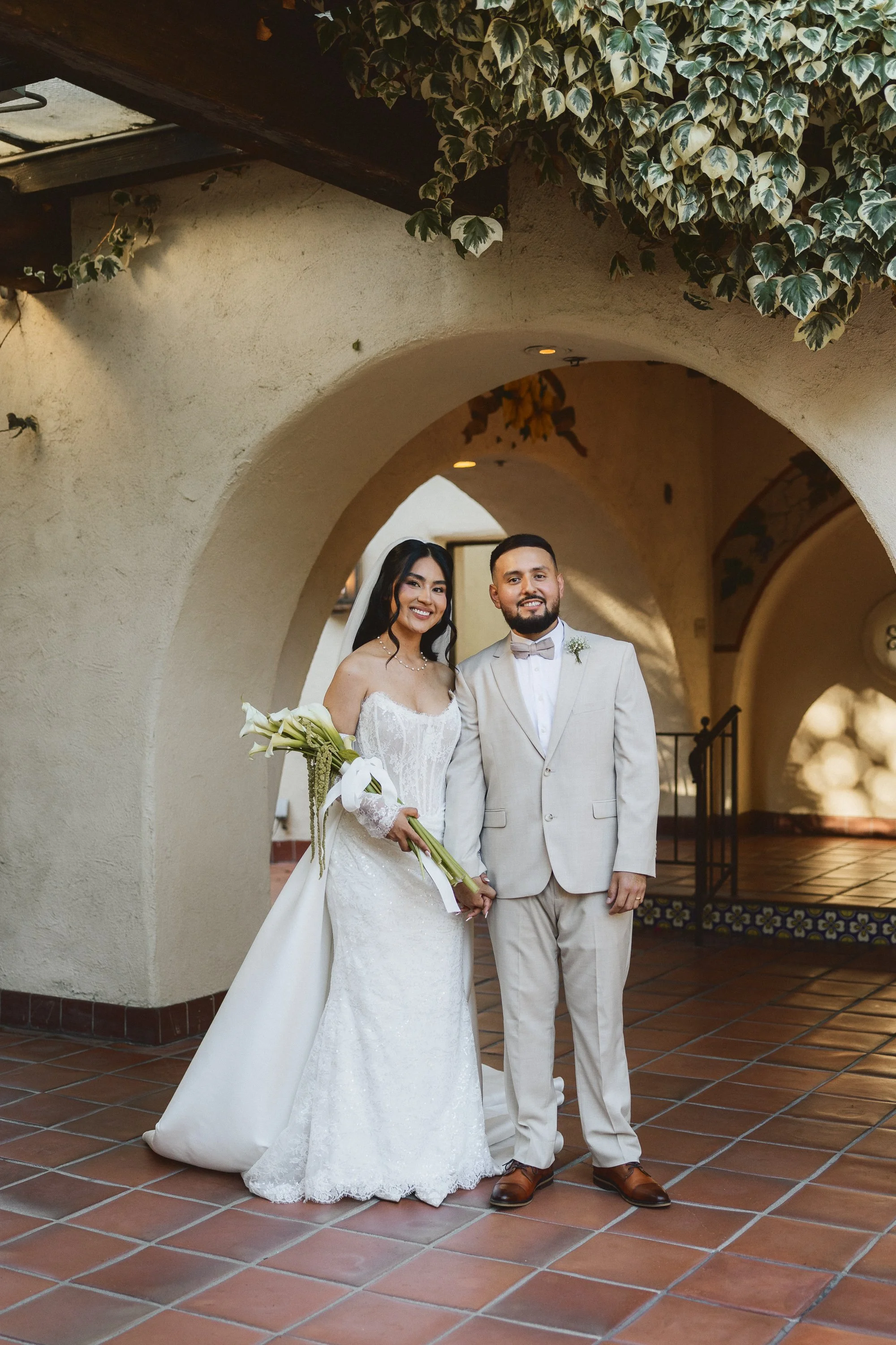 Bride and groom posing under Spanish-style arches at Los Angeles River Center and Gardens.