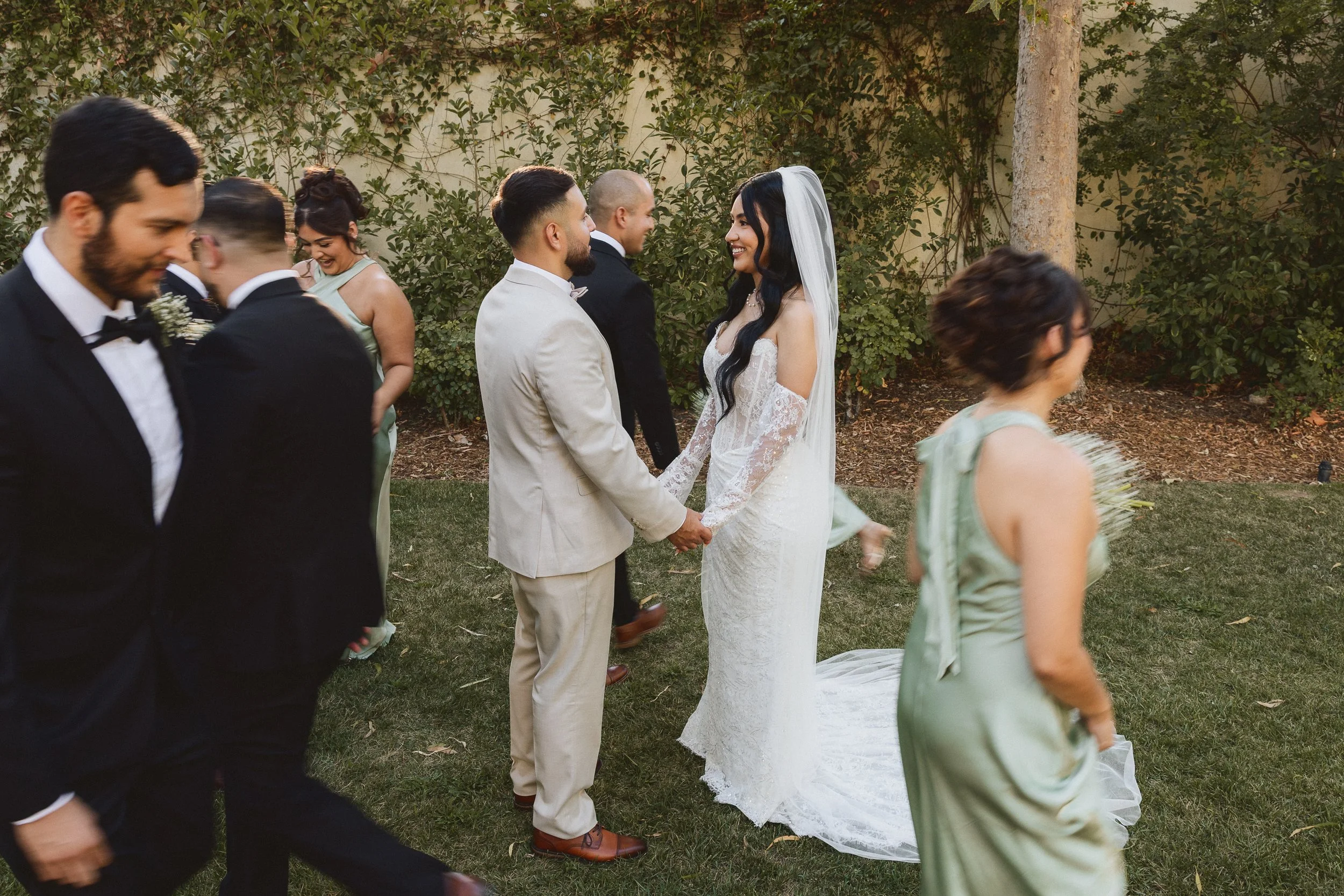 Bride and groom smiling at each other while holding hands during candid moment at Los Angeles River Center.