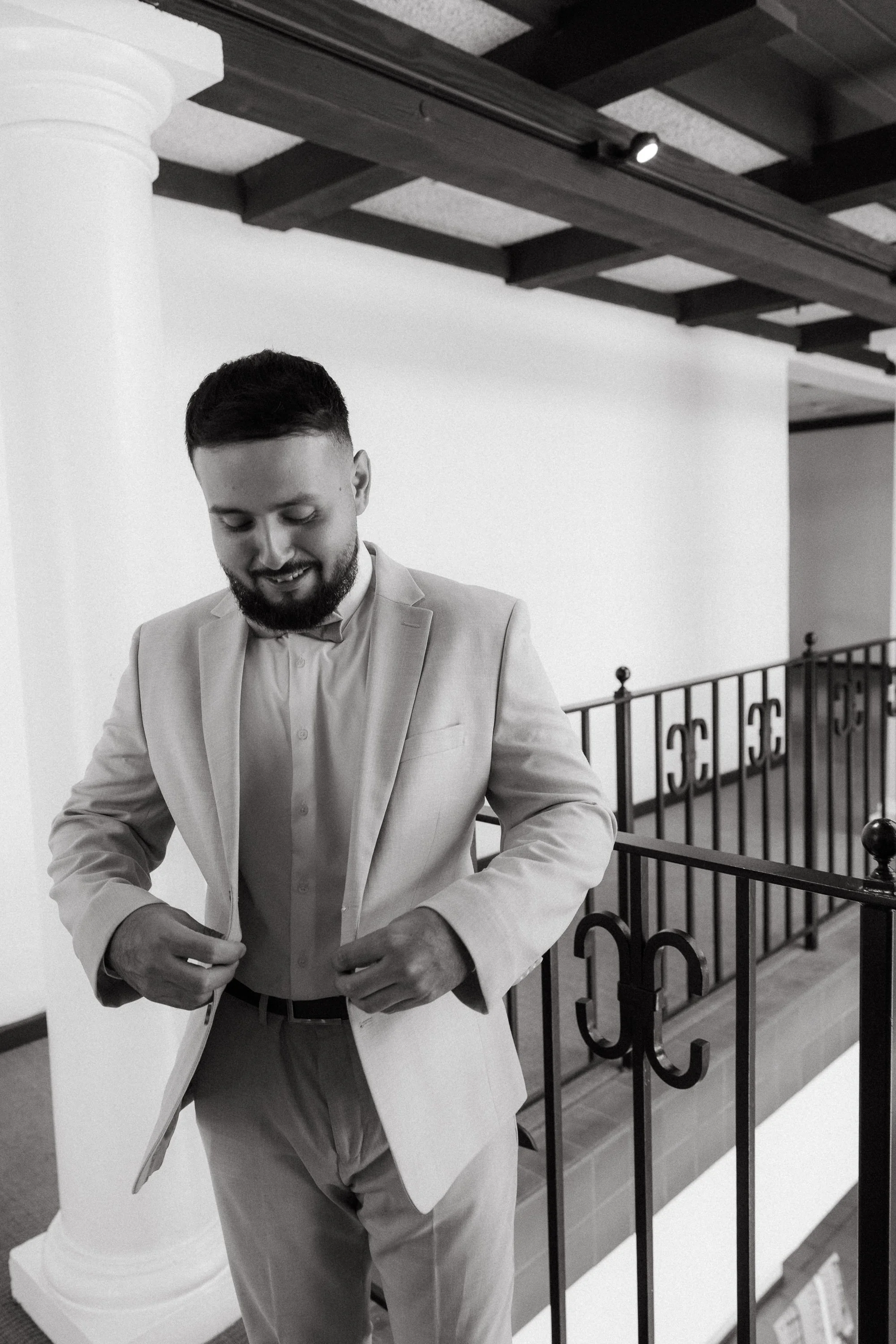 Groom buttoning jacket before wedding ceremony at Los Angeles River Center