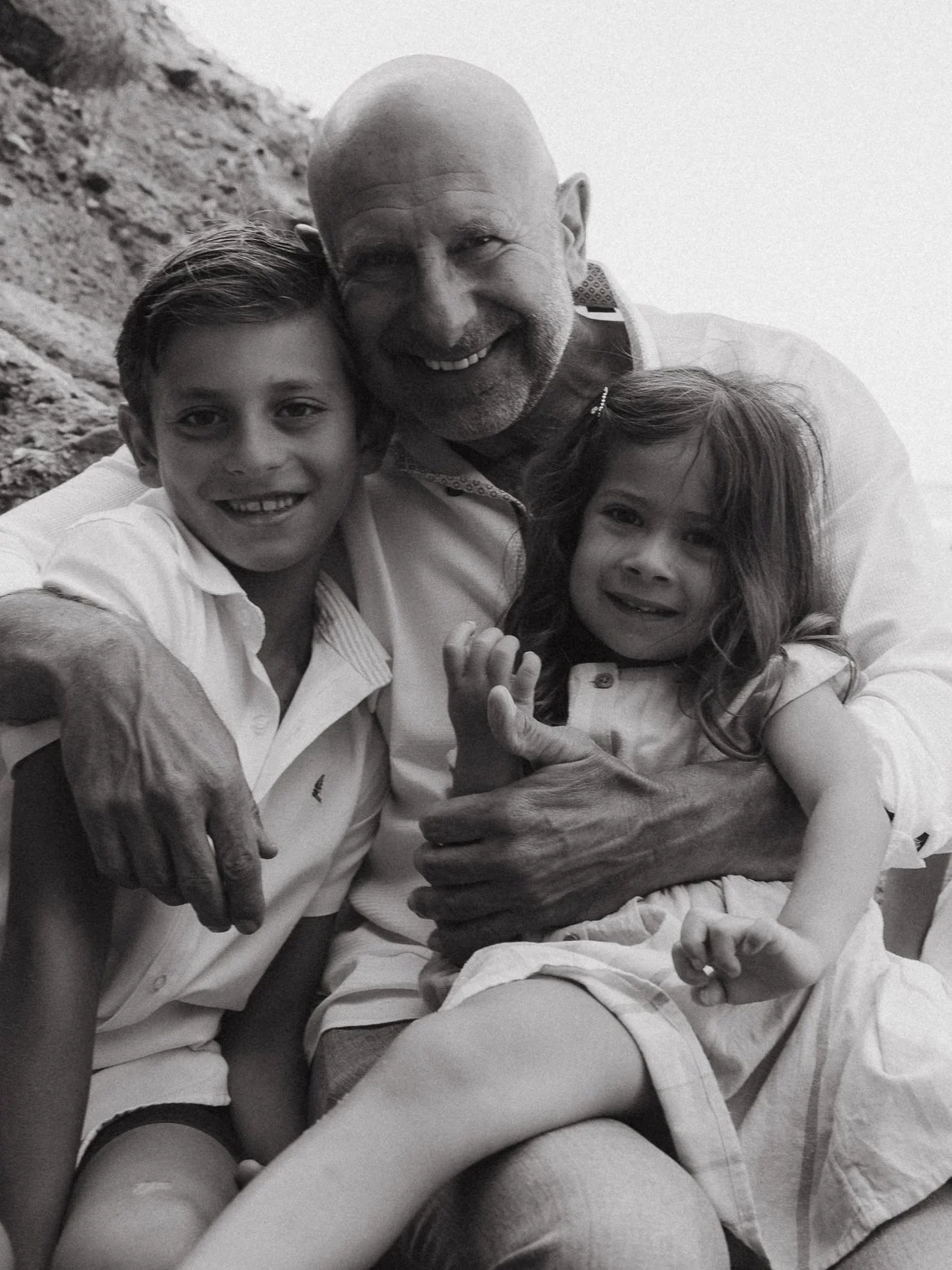 Grandfather hugs two grandchildren at sunrise on Treasure Island Beach.