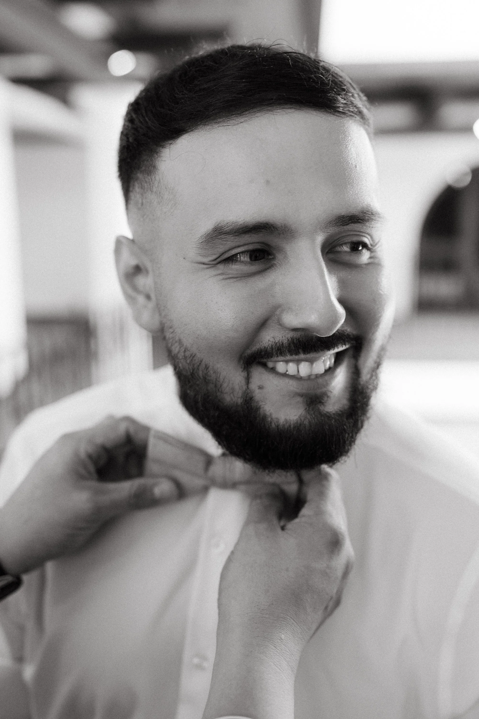Groom smiling while adjusting bow tie before ceremony