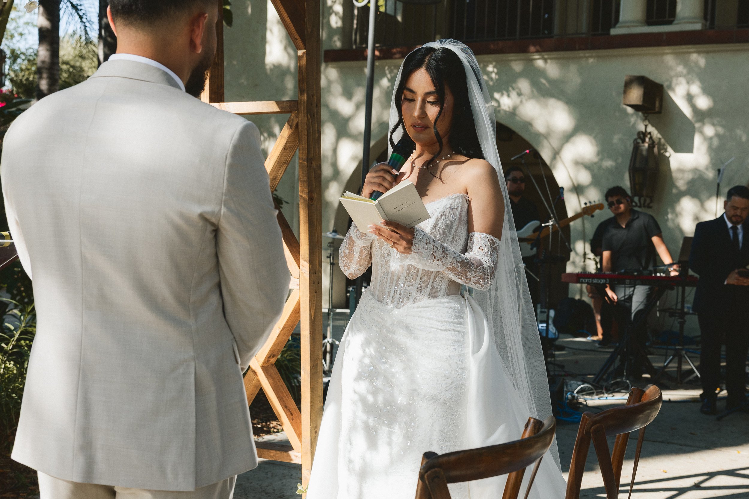 Bride reading vows to the groom during outdoor wedding ceremony at Los Angeles River Center and Gardens.