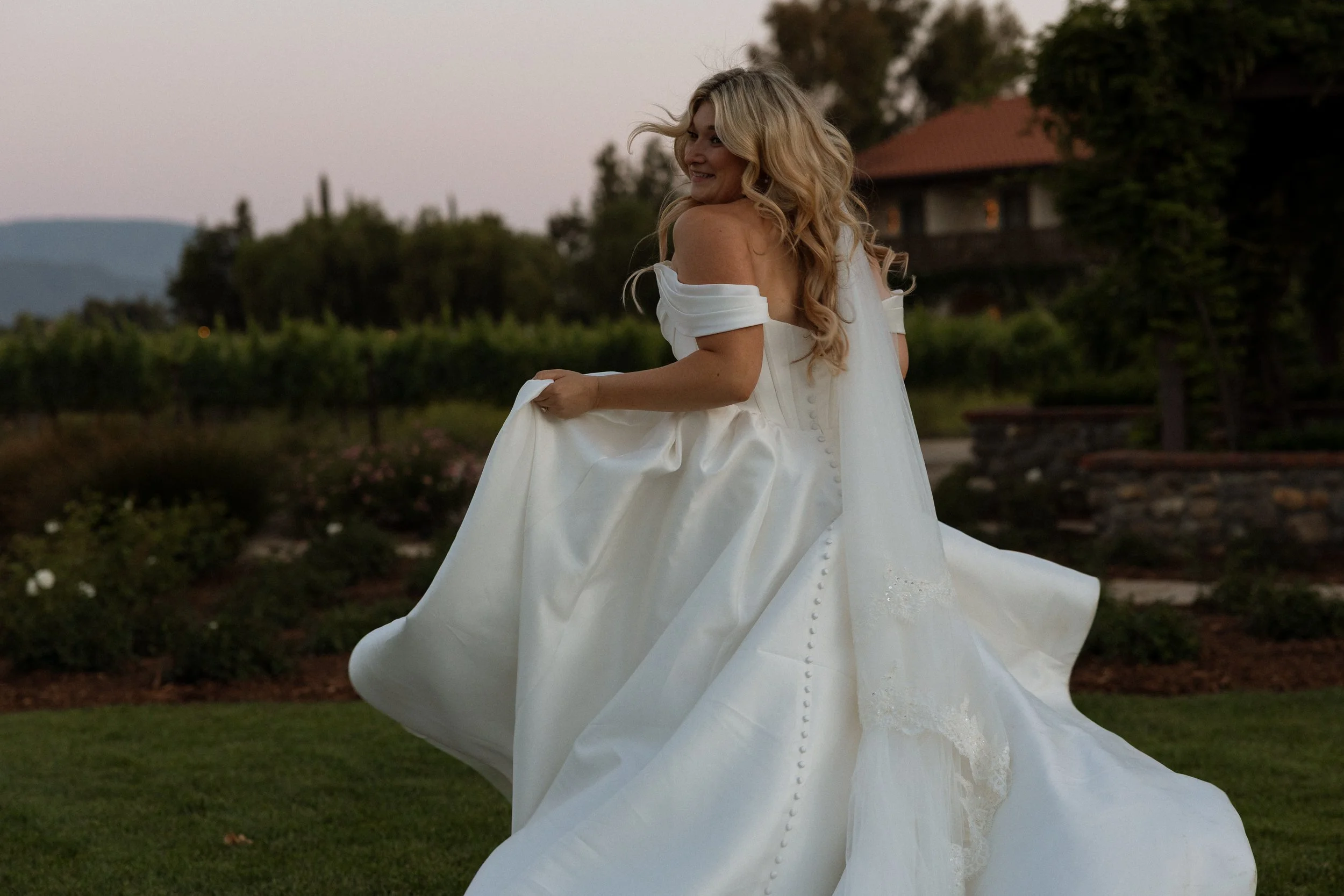 Bride glances over her shoulder as her gown sweeps around her at golden hour