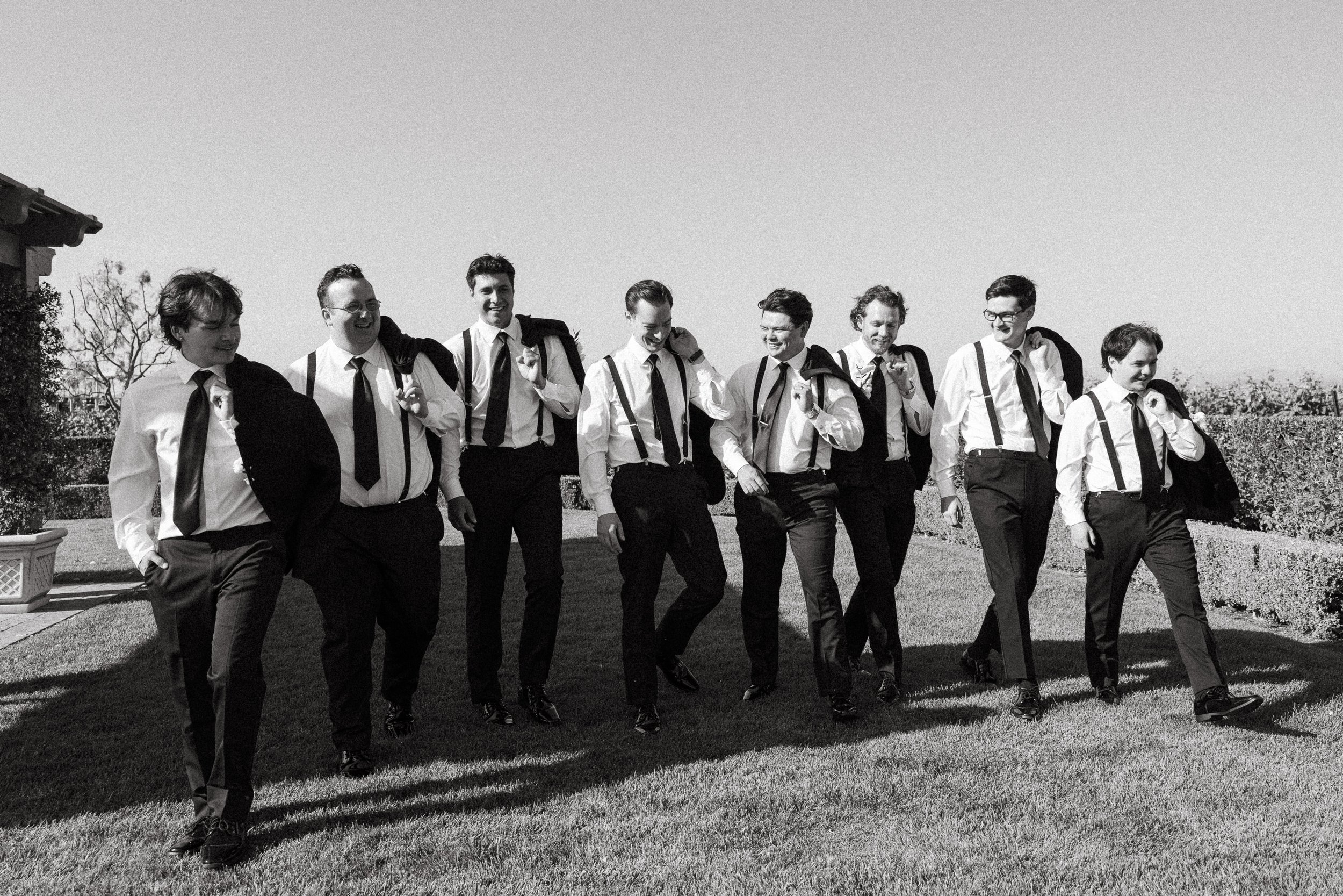 Groomsmen in suspenders walking and laughing after the wedding ceremony