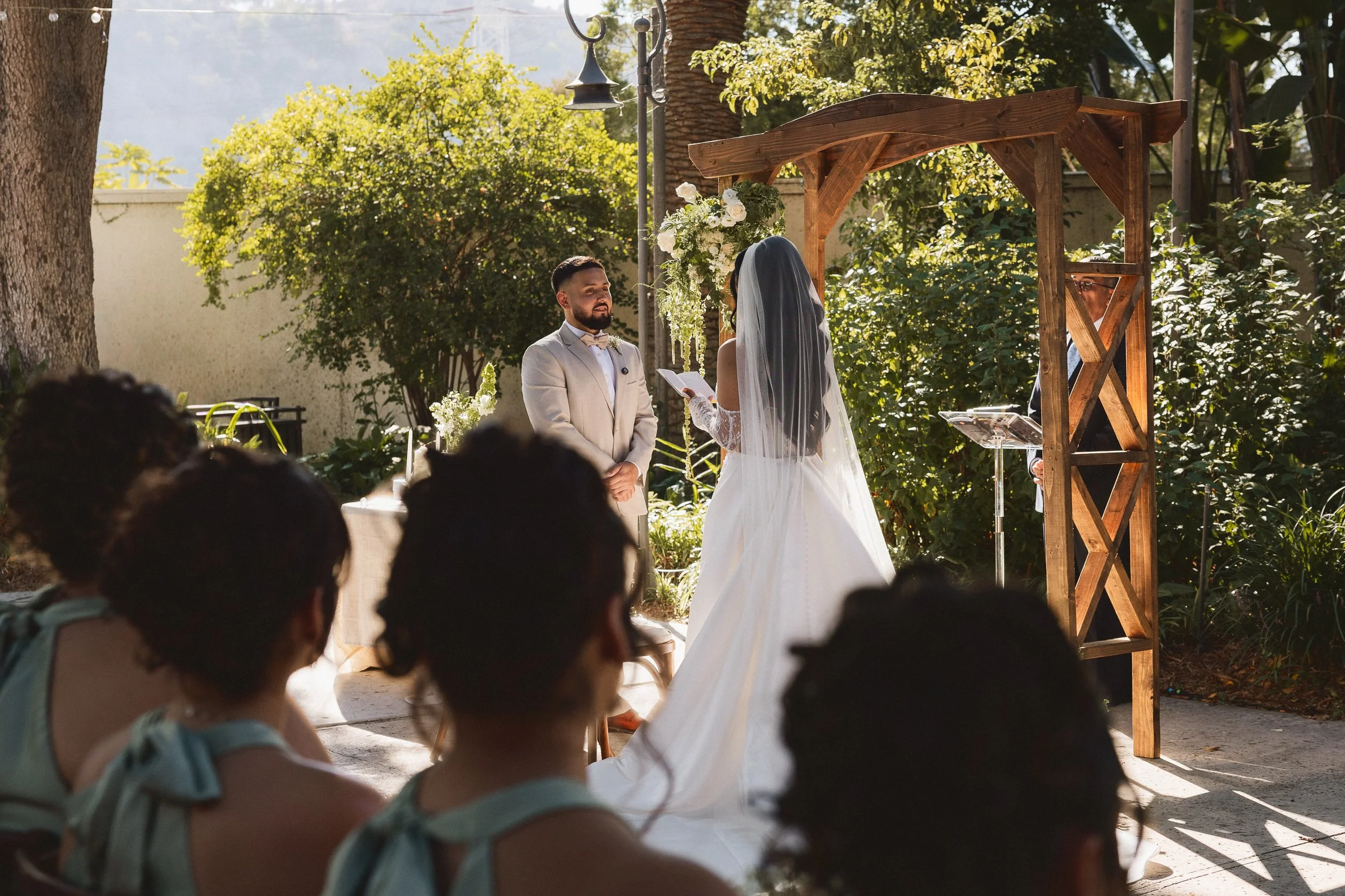 Groom smiling at the bride as she shares vows at Los Angeles River Center and Gardens.