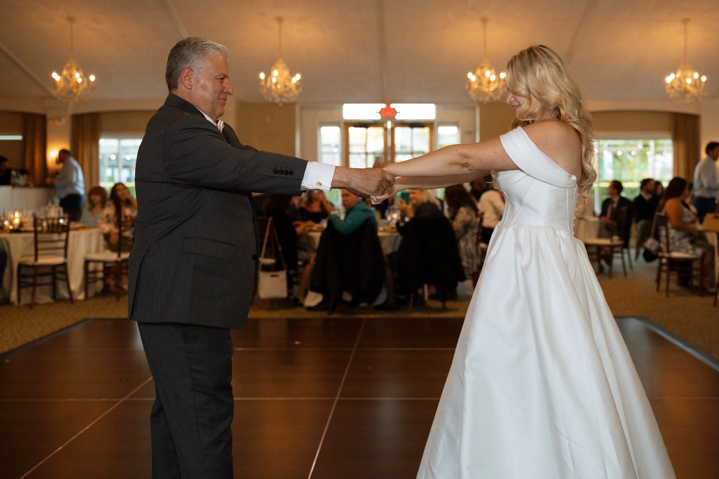 Bride and her father dance hand in hand at the reception
