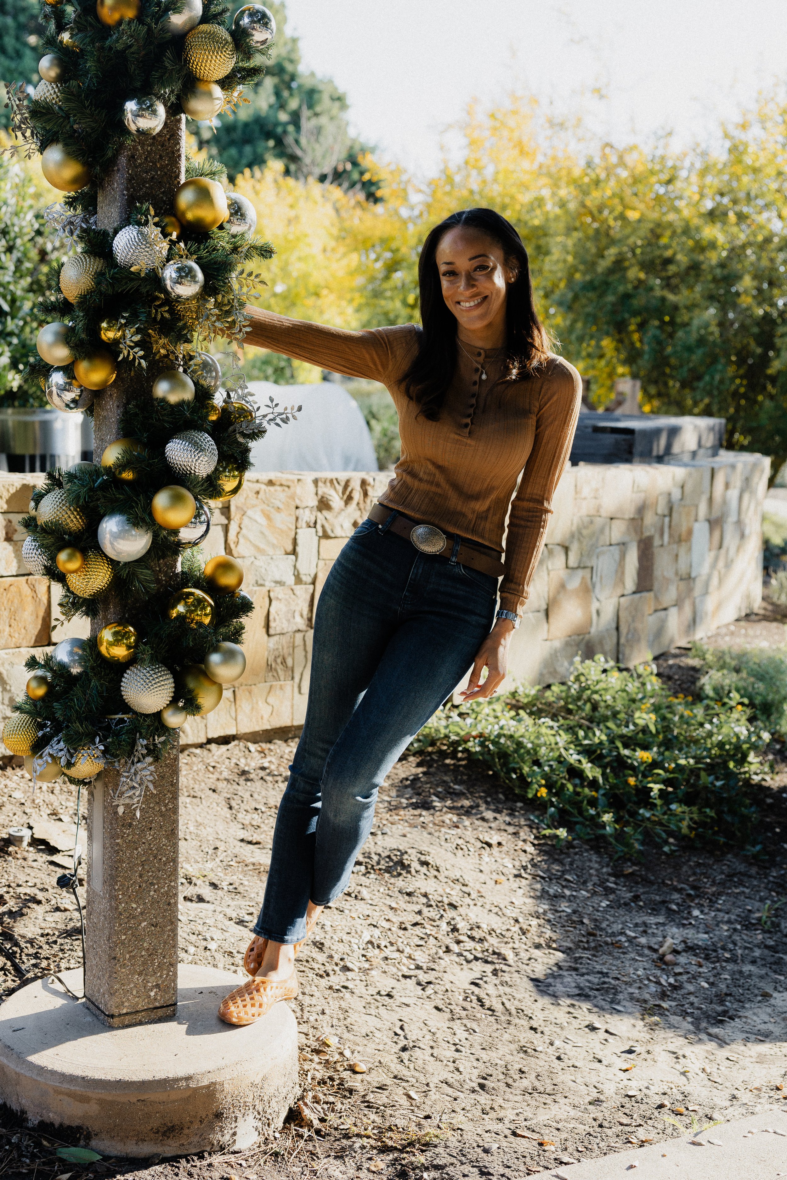 Ashley Young leaning against a festive post decorated with gold and silver Christmas ornaments at Pavilion Park in Irvine.