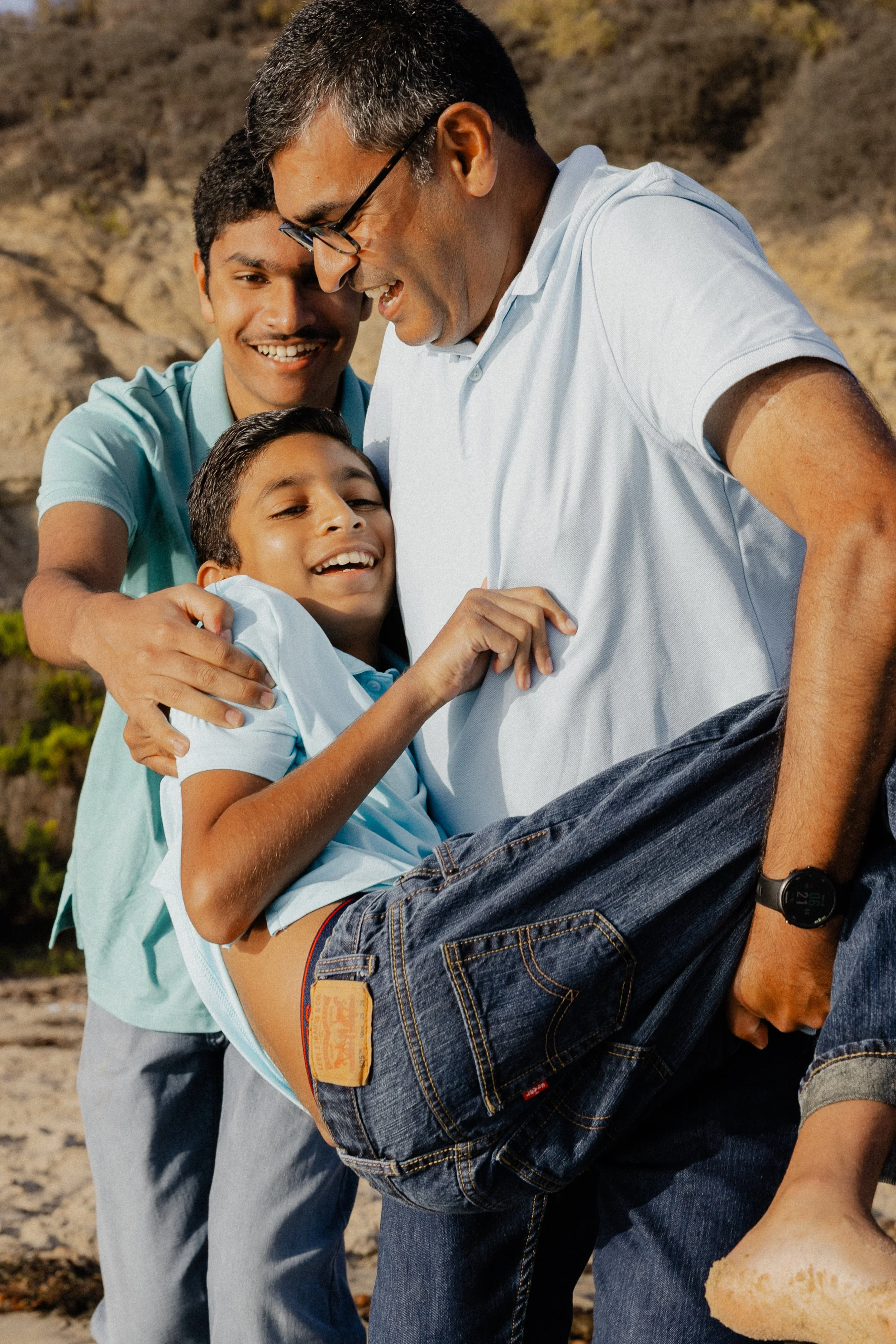 Father carrying his son while smiling during Newport Beach family photography at Crystal Cove.