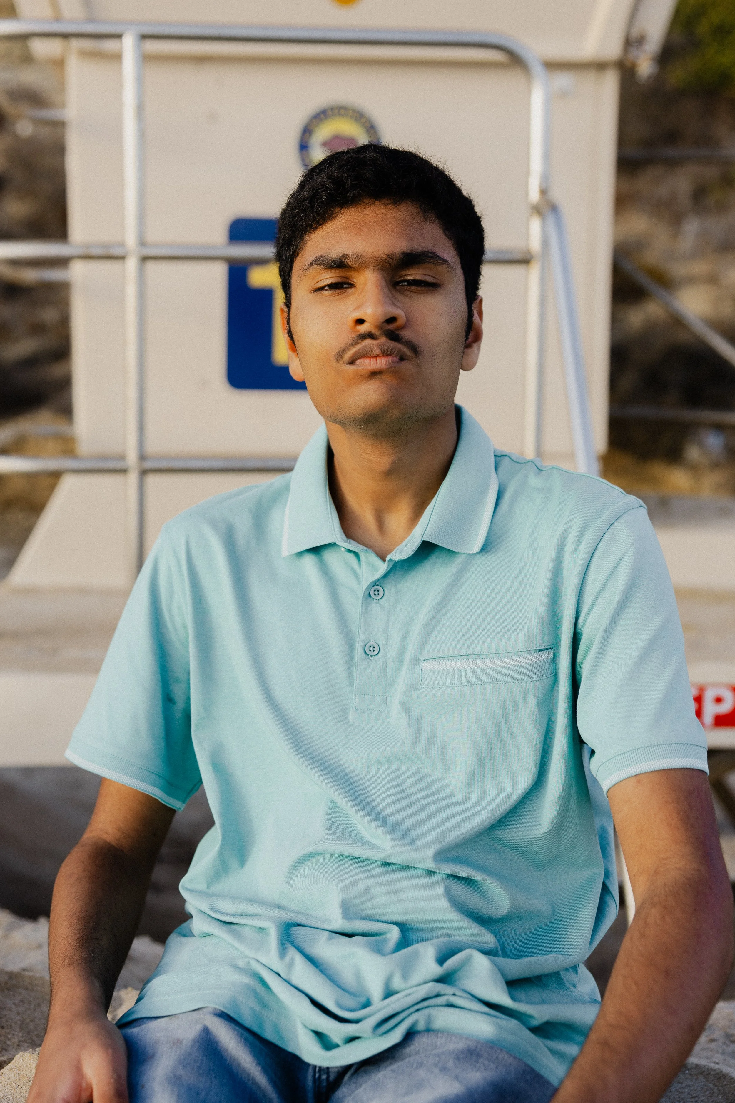 Close-up portrait of a teenage boy sitting near the lifeguard tower at Crystal Cove State Park.