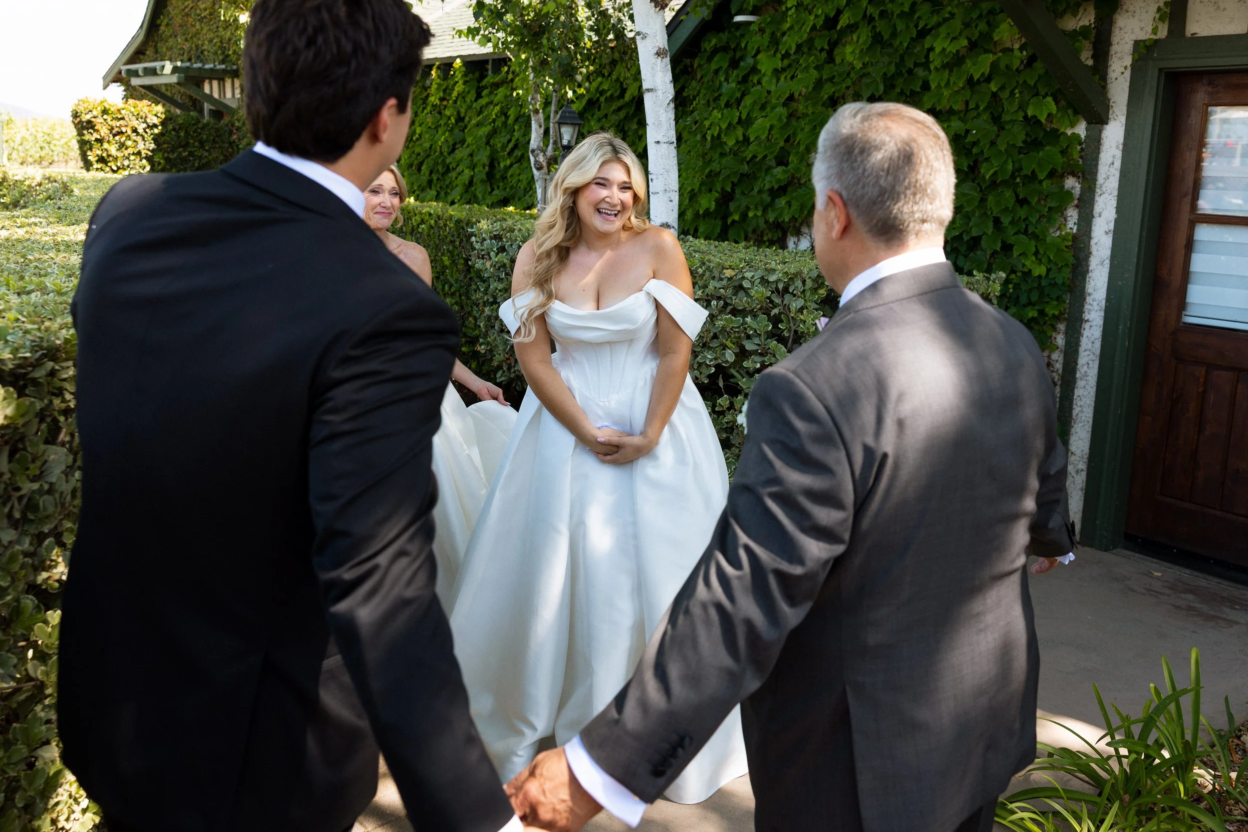 Bride laughs during a first-look reveal as family turns to see her gown