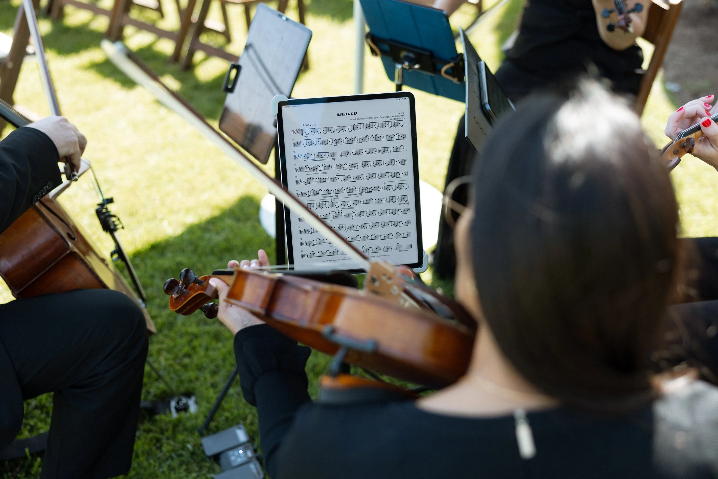 A violinist plays from sheet music during the outdoor ceremony