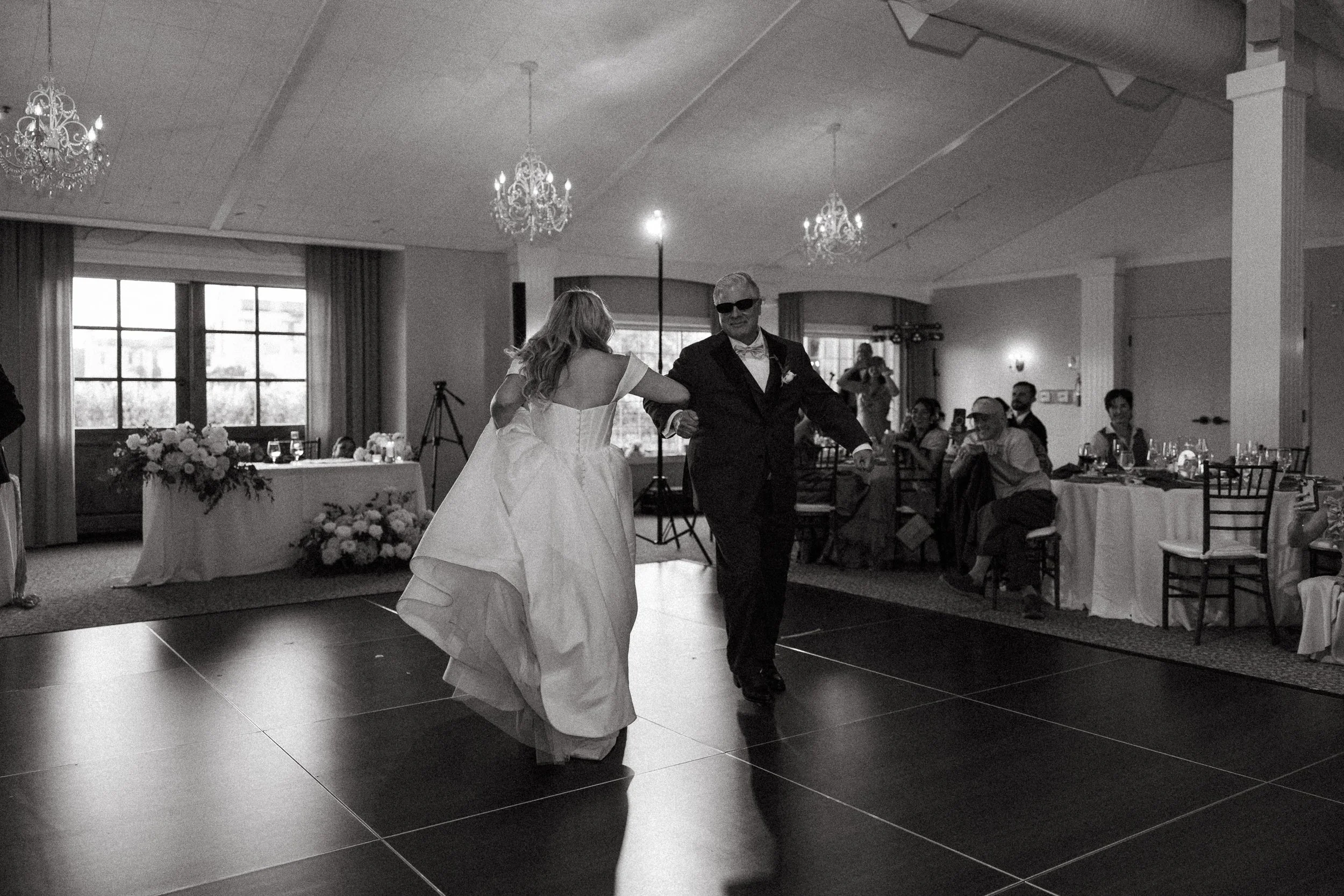 Bride twirls onto the dance floor with her father in black and white