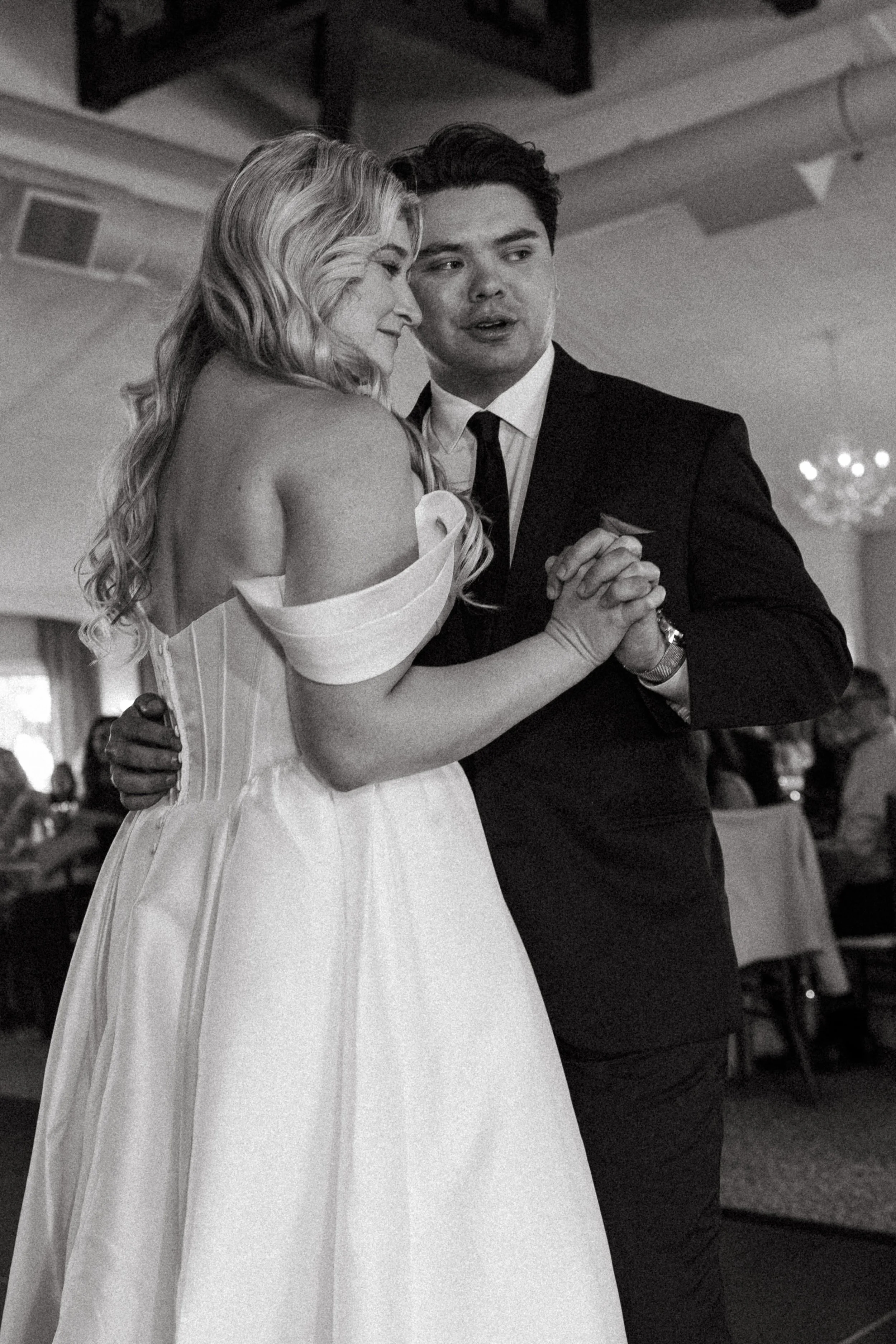 Bride and groom share a close, tender first dance in black and white