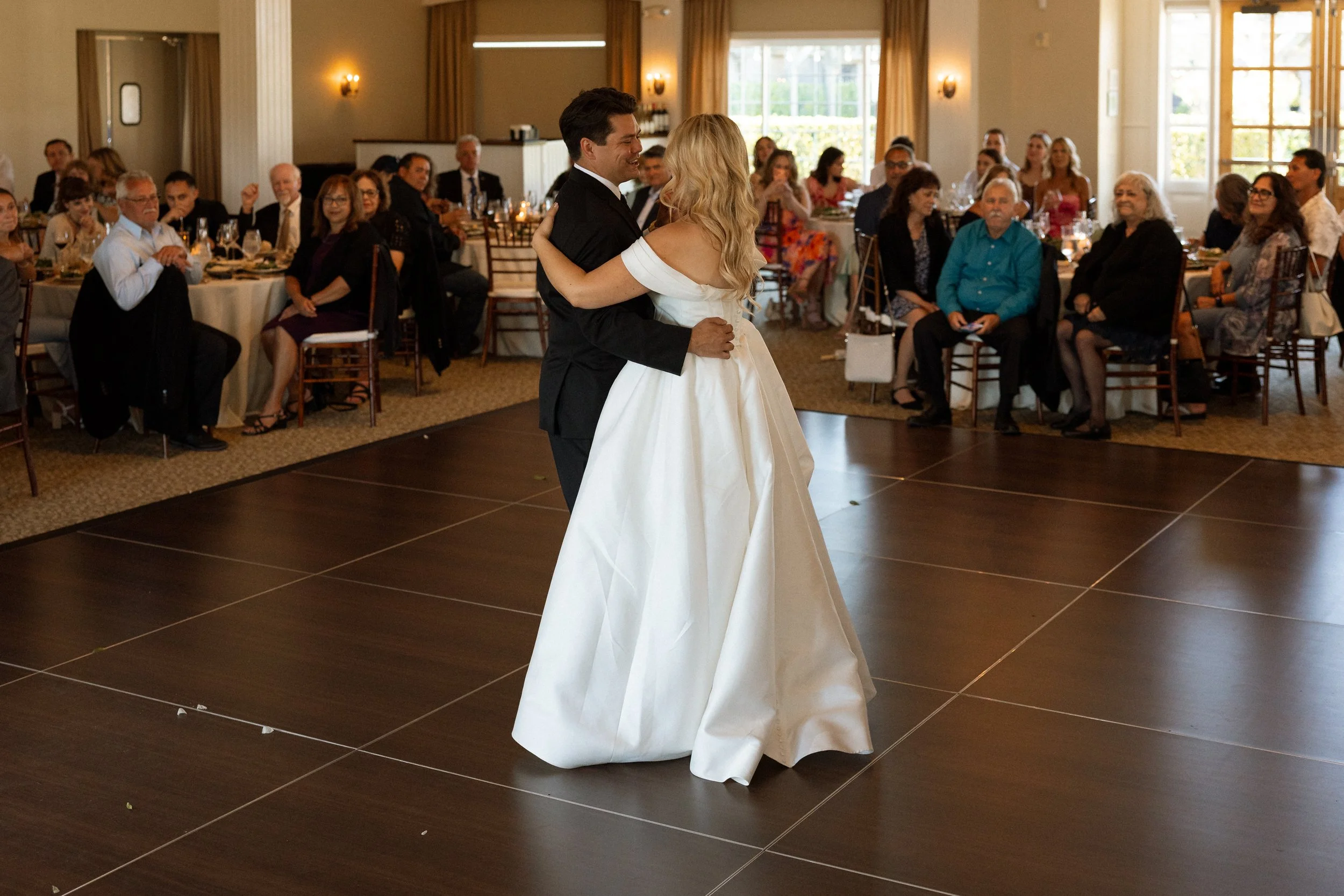 Couple's first dance on the floor as seated guests look on