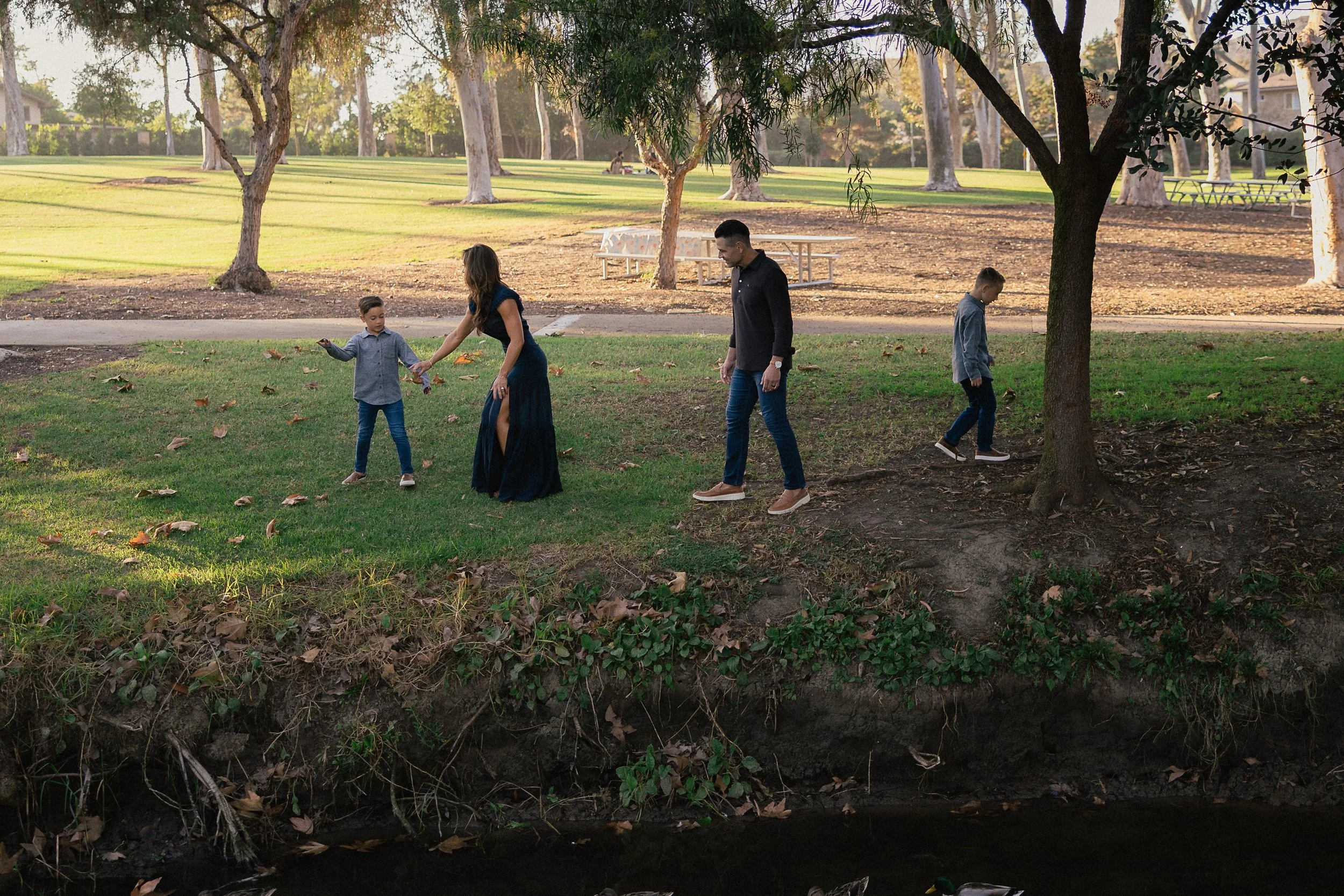 Family standing along the creek watching ducks in the water at Turtle Rock Park.