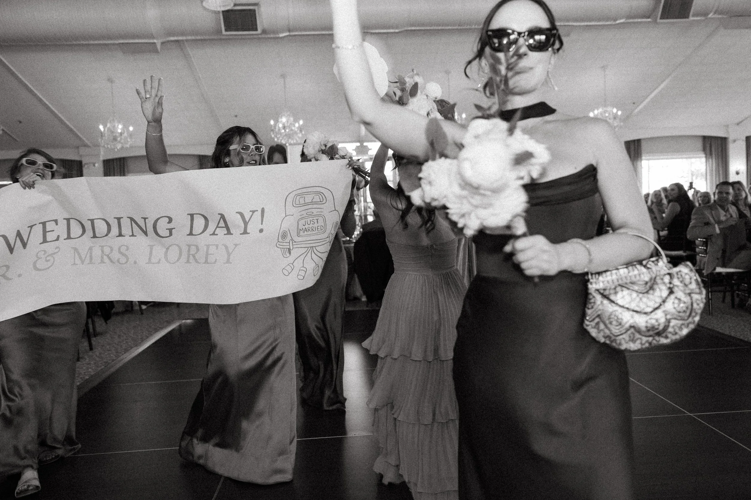 Bridal party dances in with a "Just Married" banner to open the reception
