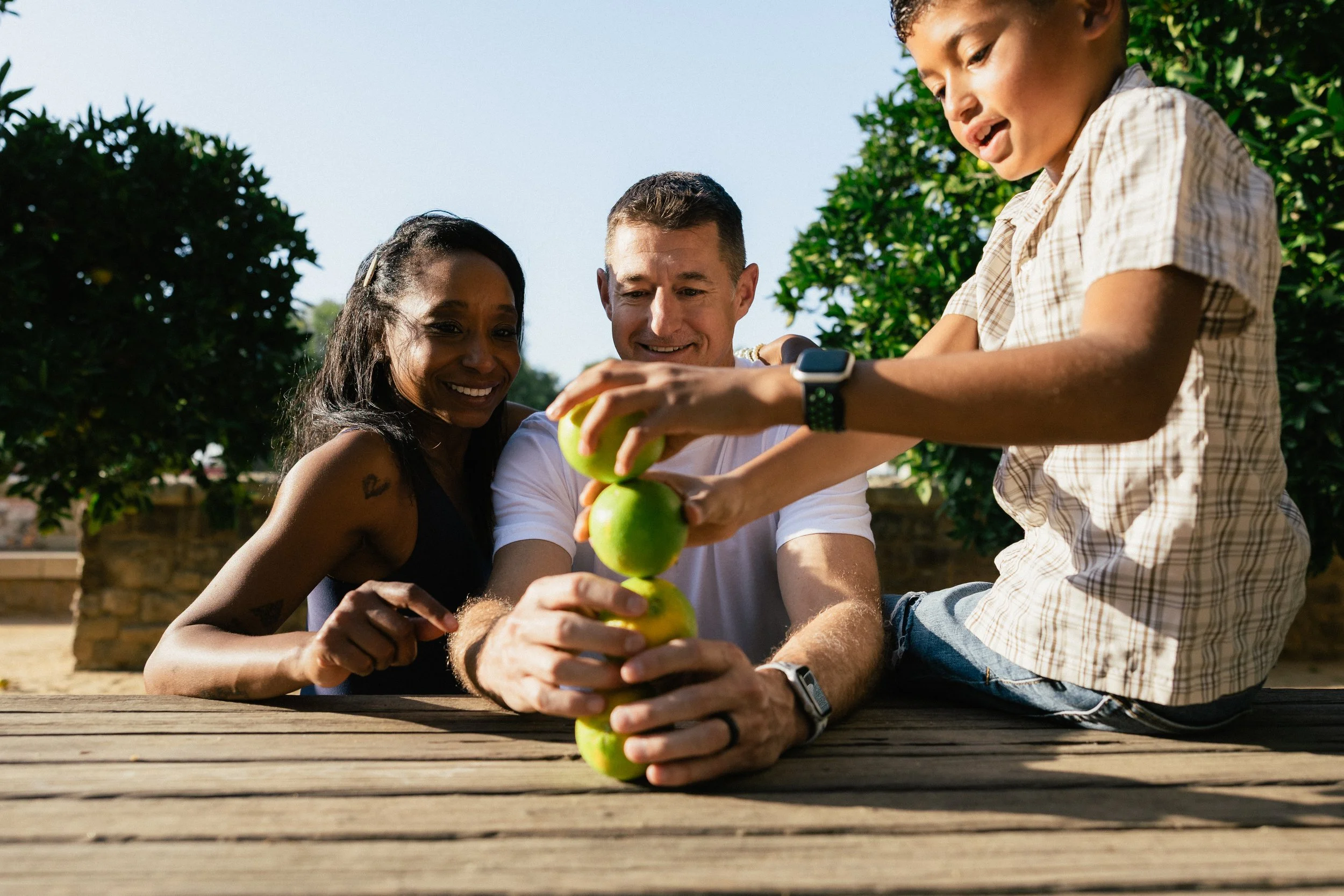 A candid moment of a family stacking lemons and laughing together at a picnic table during a session at Jeffrey Open Space Trail in Irvine.