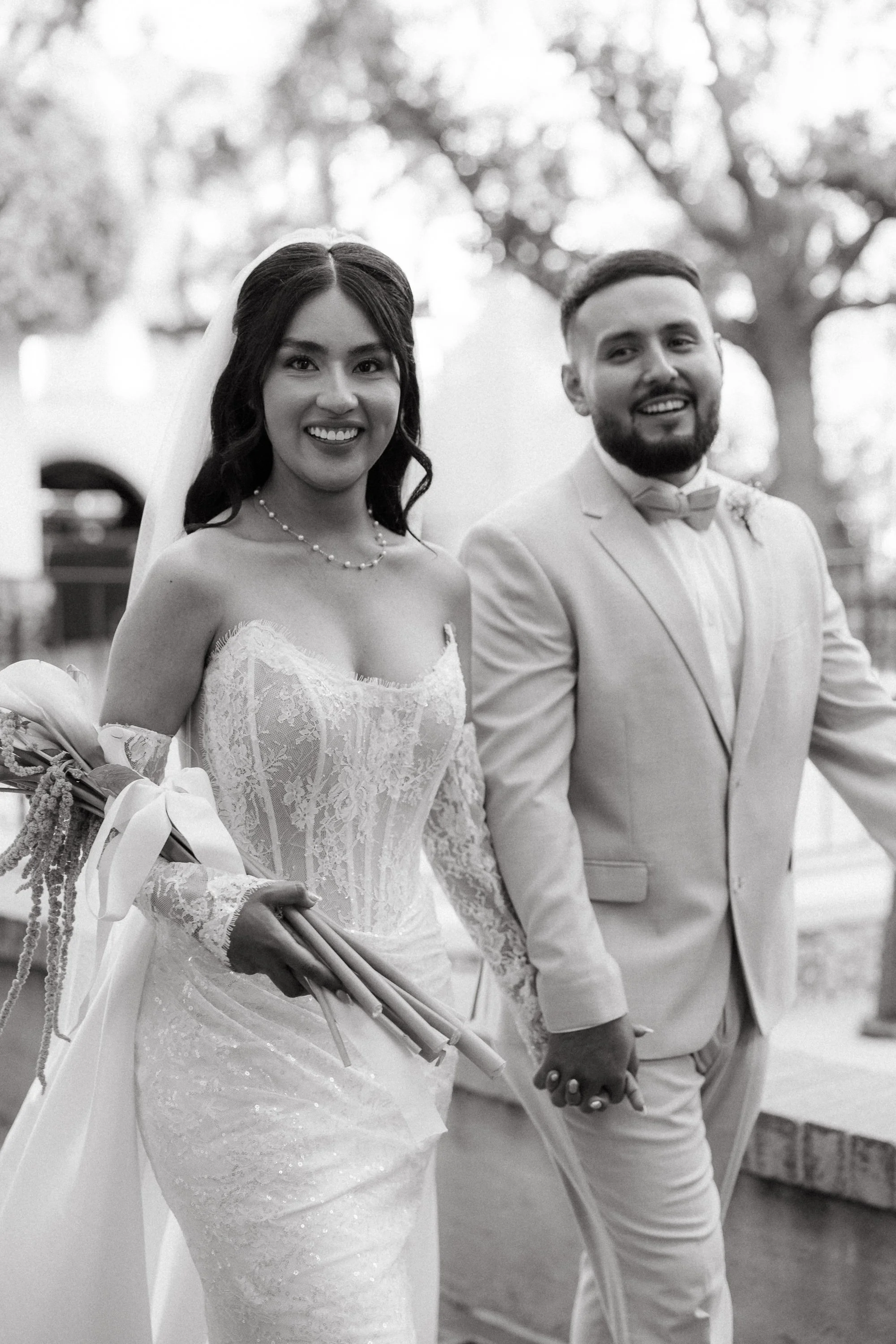 Black and white photo of bride and groom walking hand in hand at Los Angeles River Center and Gardens.