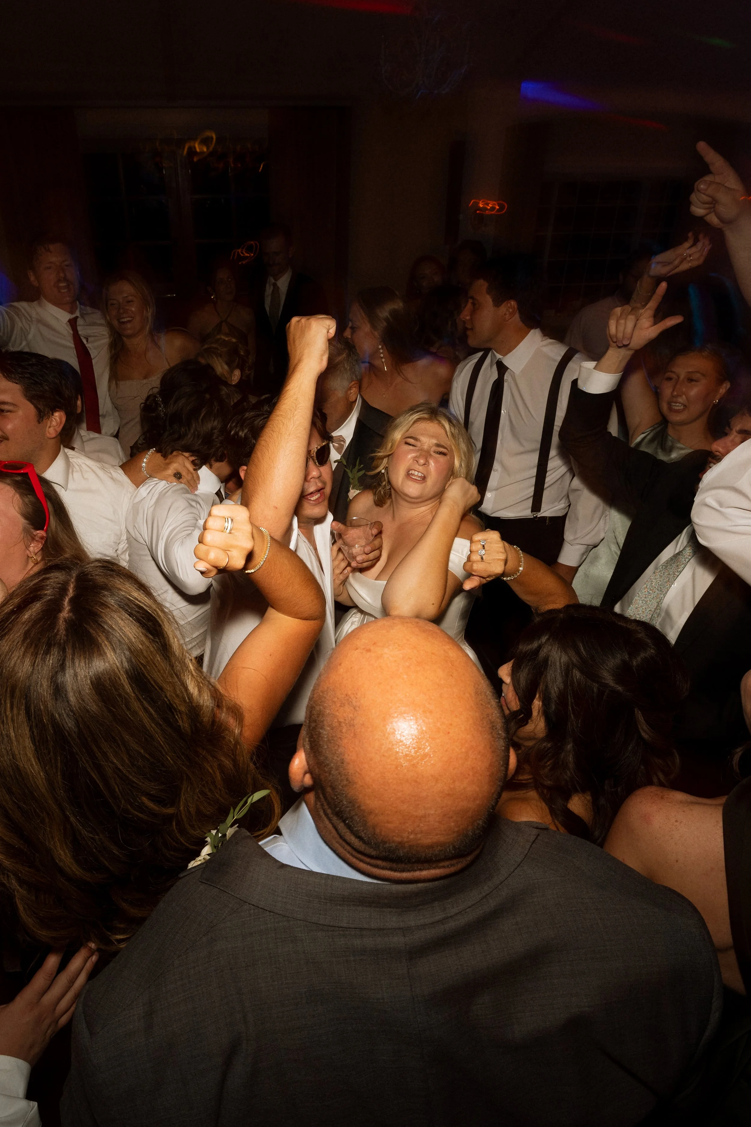 Bride dances arm in arm surrounded by guests on a packed floor