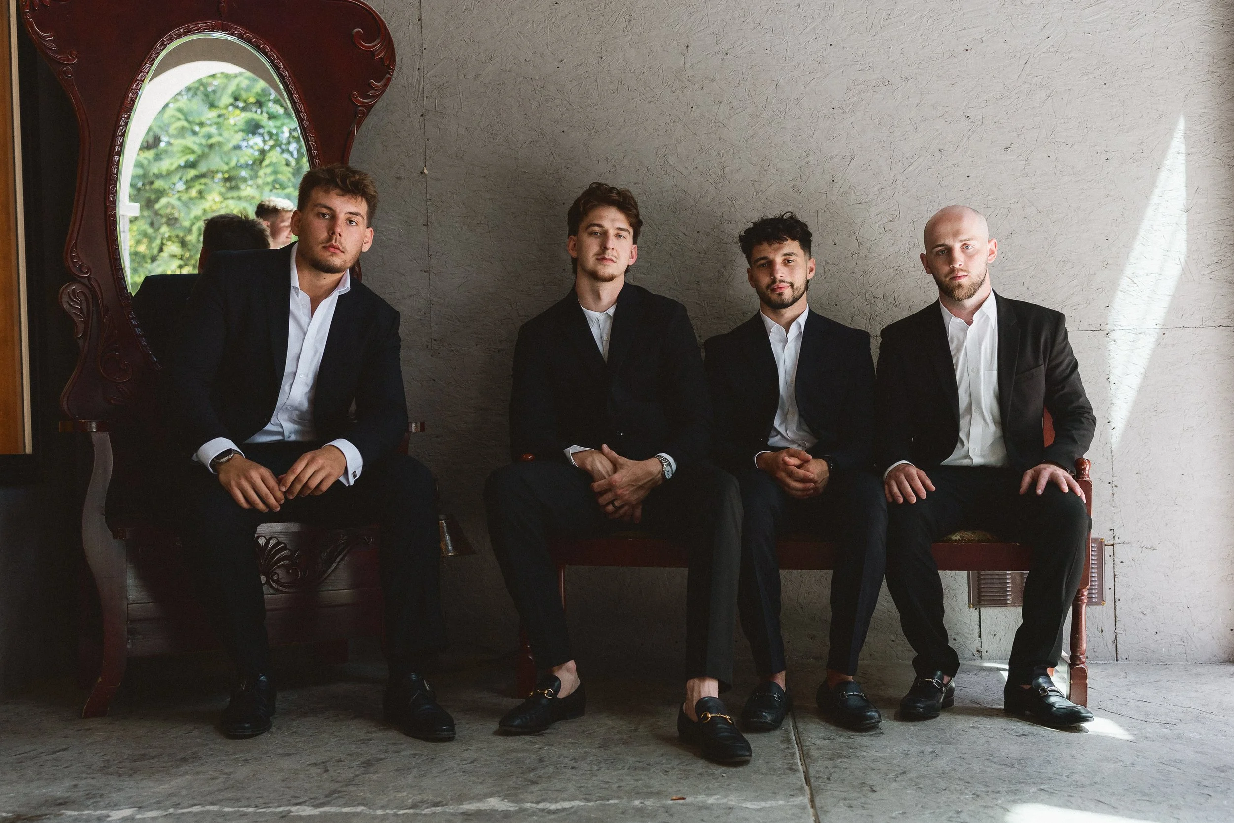 Groom and groomsmen sitting together before the ceremony, dressed in suits.