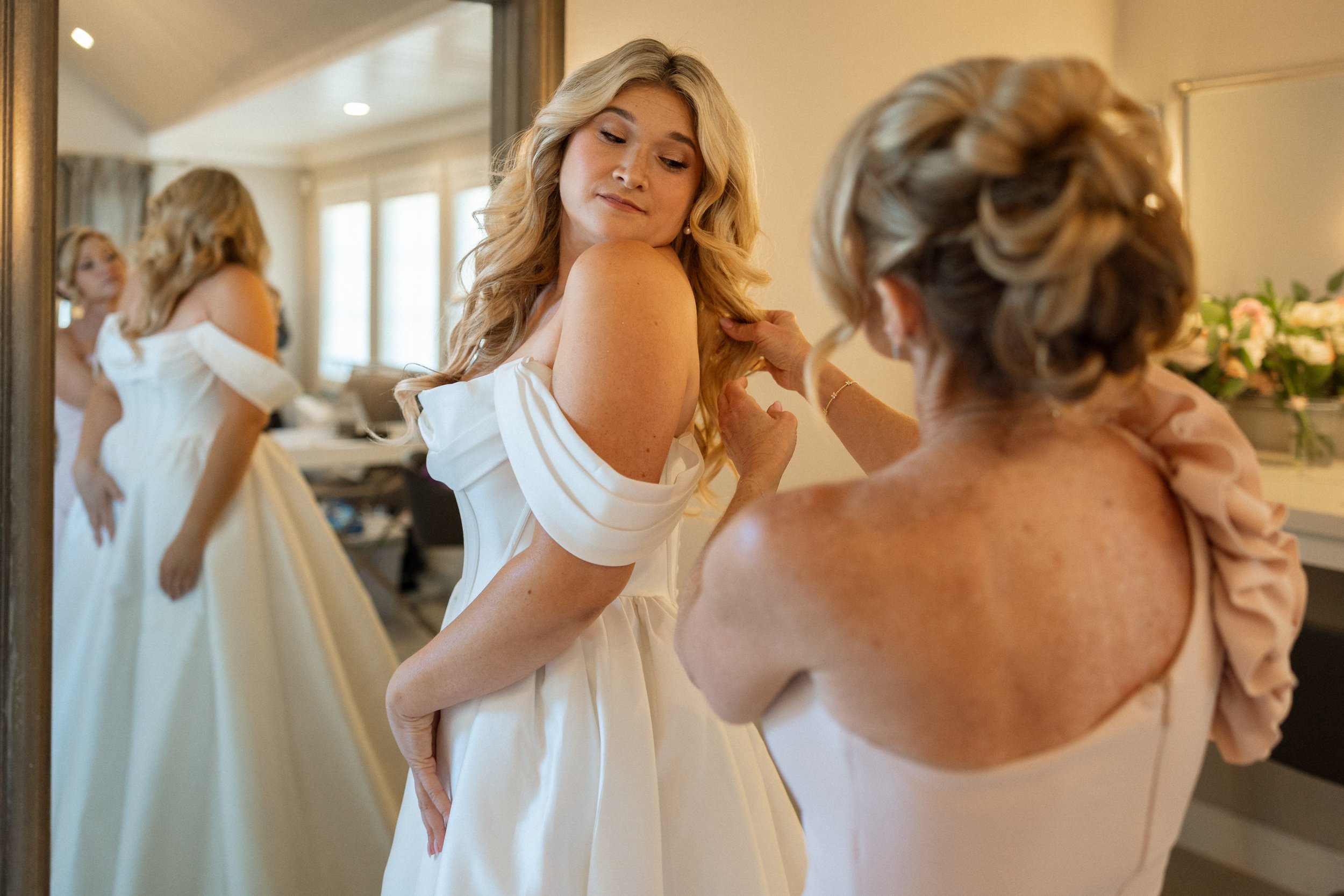 Bride glances over her shoulder while final touches are made to her hair