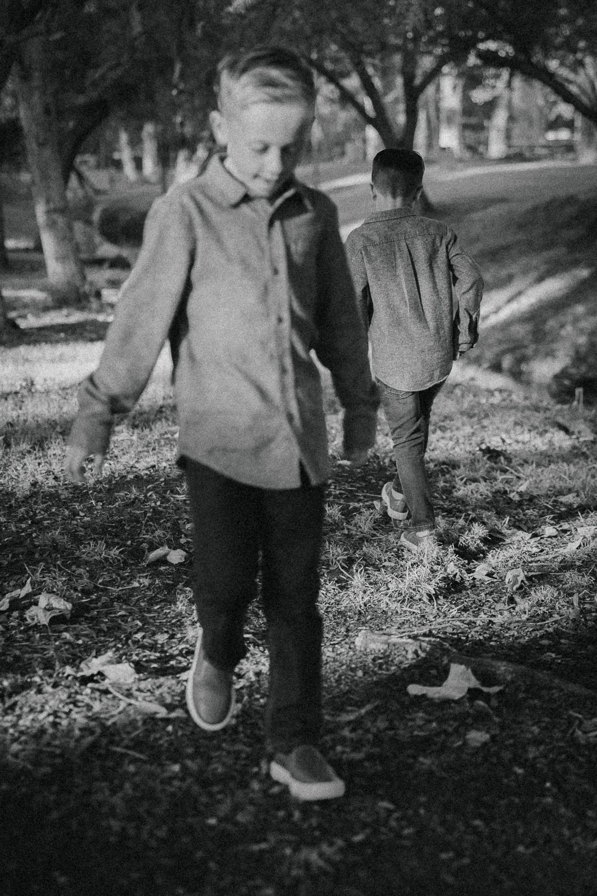 Young boys walking near the creek area with trees and soft shadows behind him.