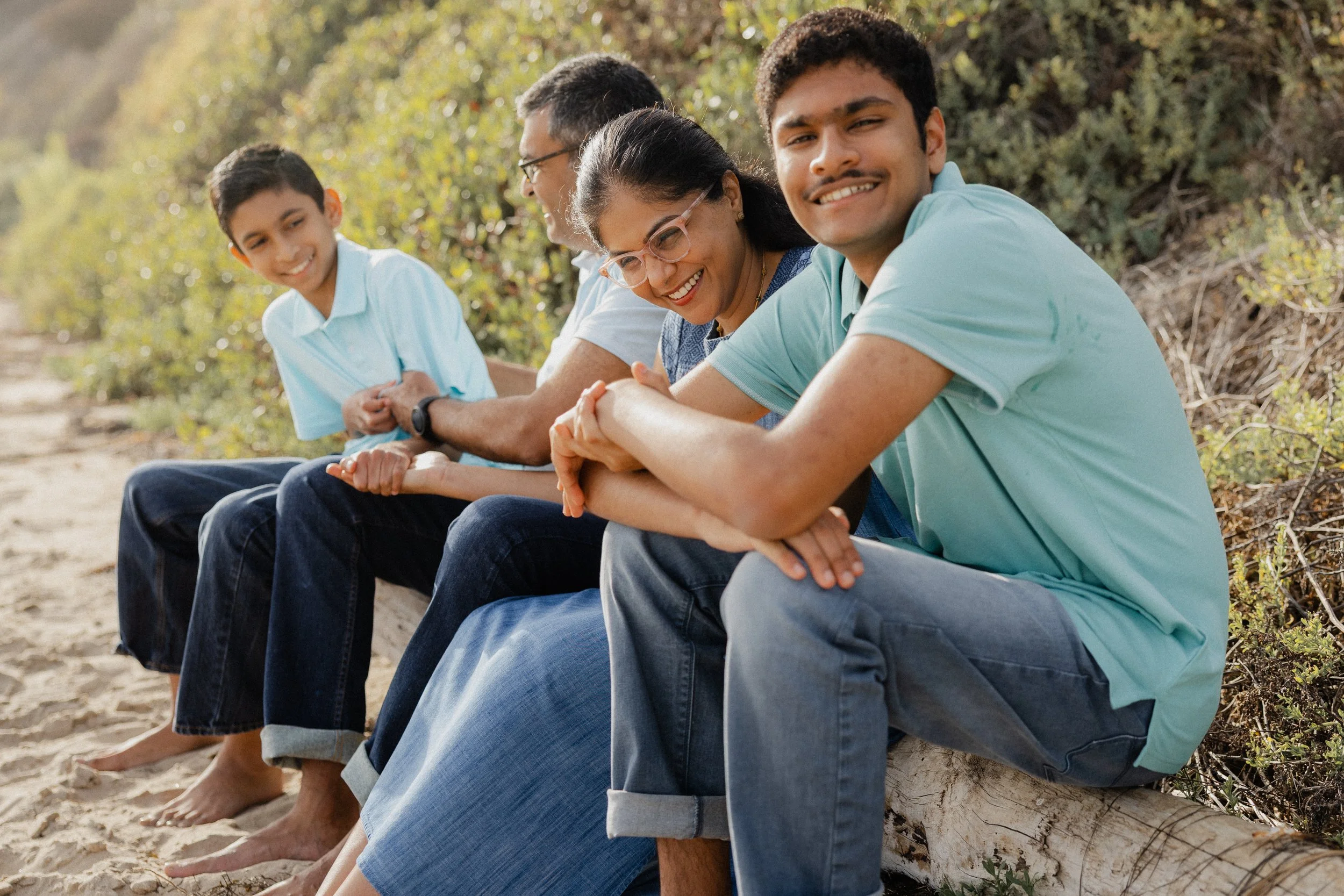 Parents and their sons smiling together during family photos at Crystal Cove State Park in Newport Beach.