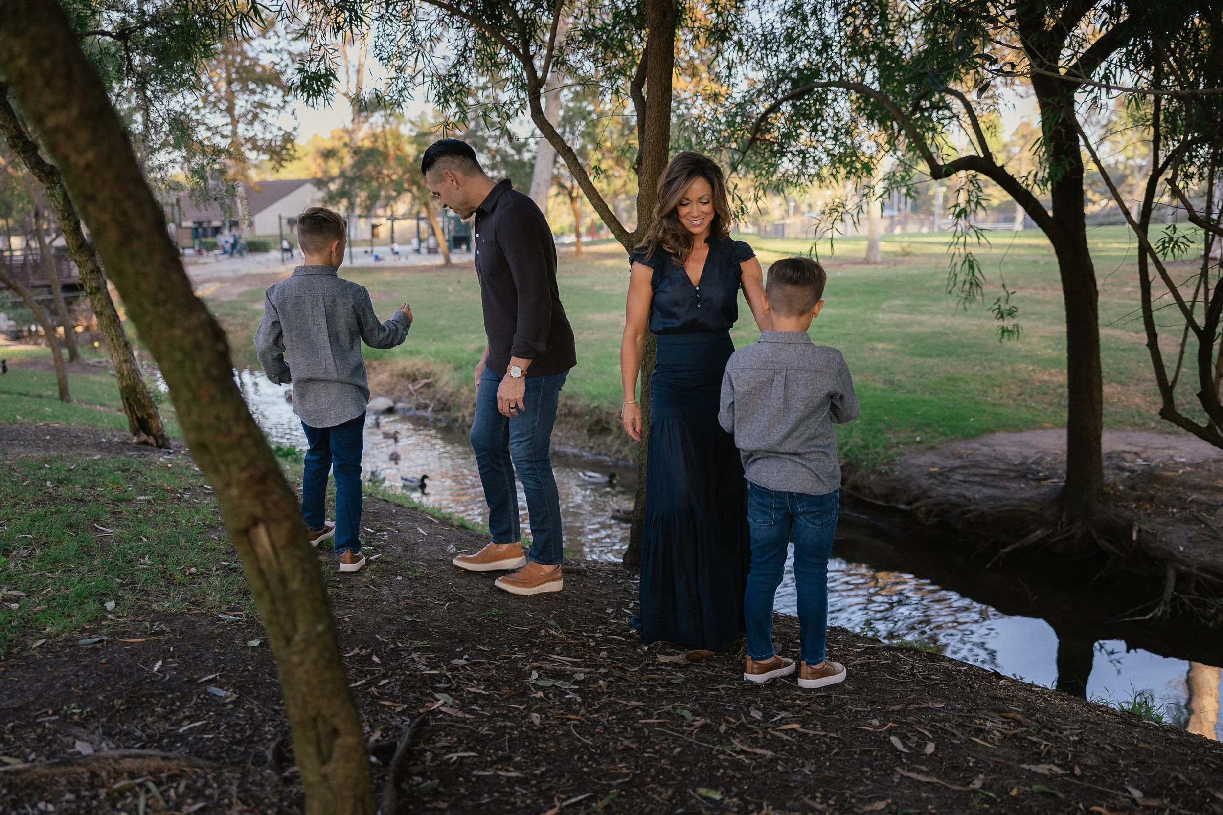 Family exploring along the creek as the kids pick up small objects on the ground.