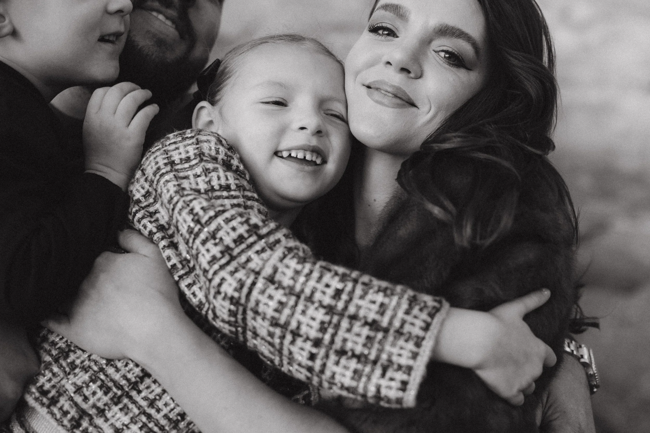 A black and white close-up of a mother embracing her children during a candid family photography session at Treasure Island Beach.