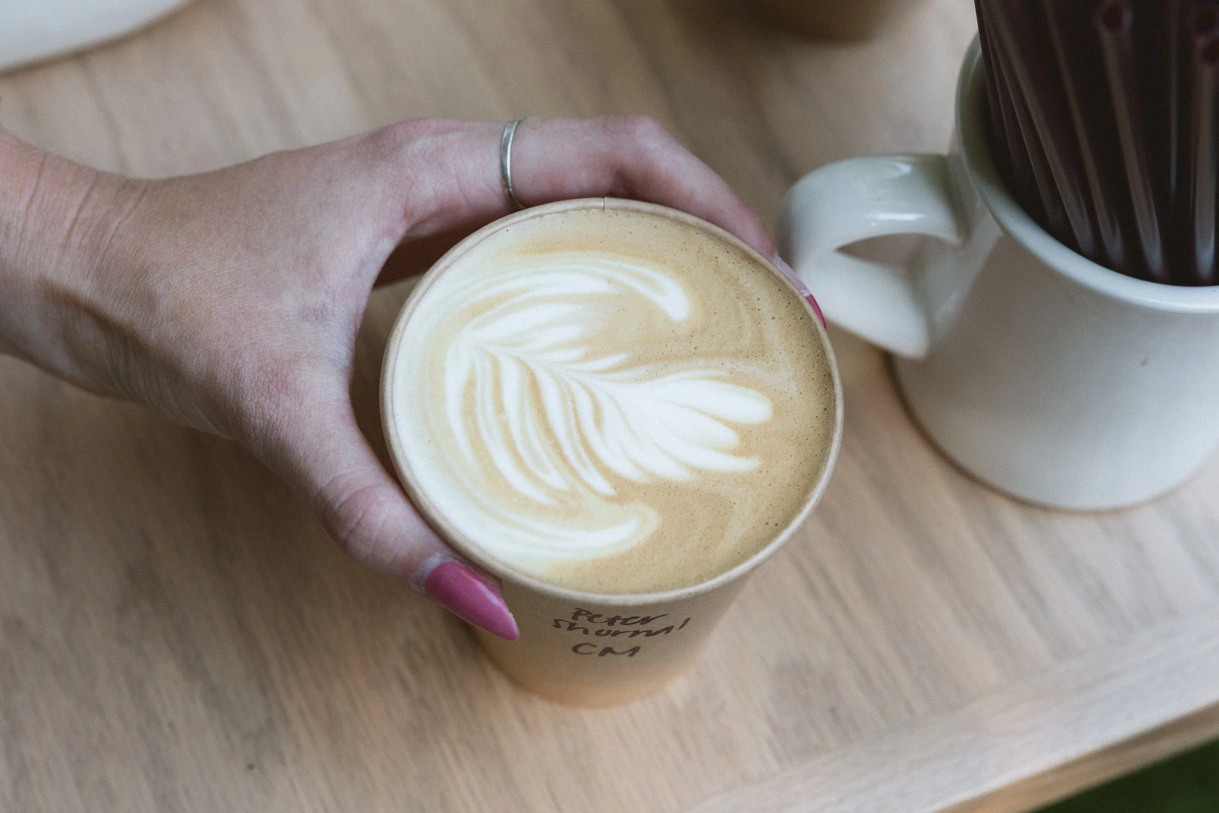 Hand holding a latte with foam art at the coffee cart