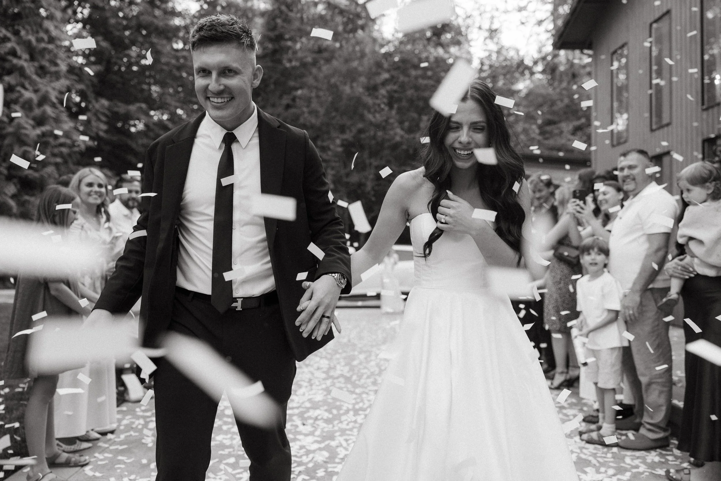 Bride and groom walk through a tunnel of guests throwing confetti after ceremony