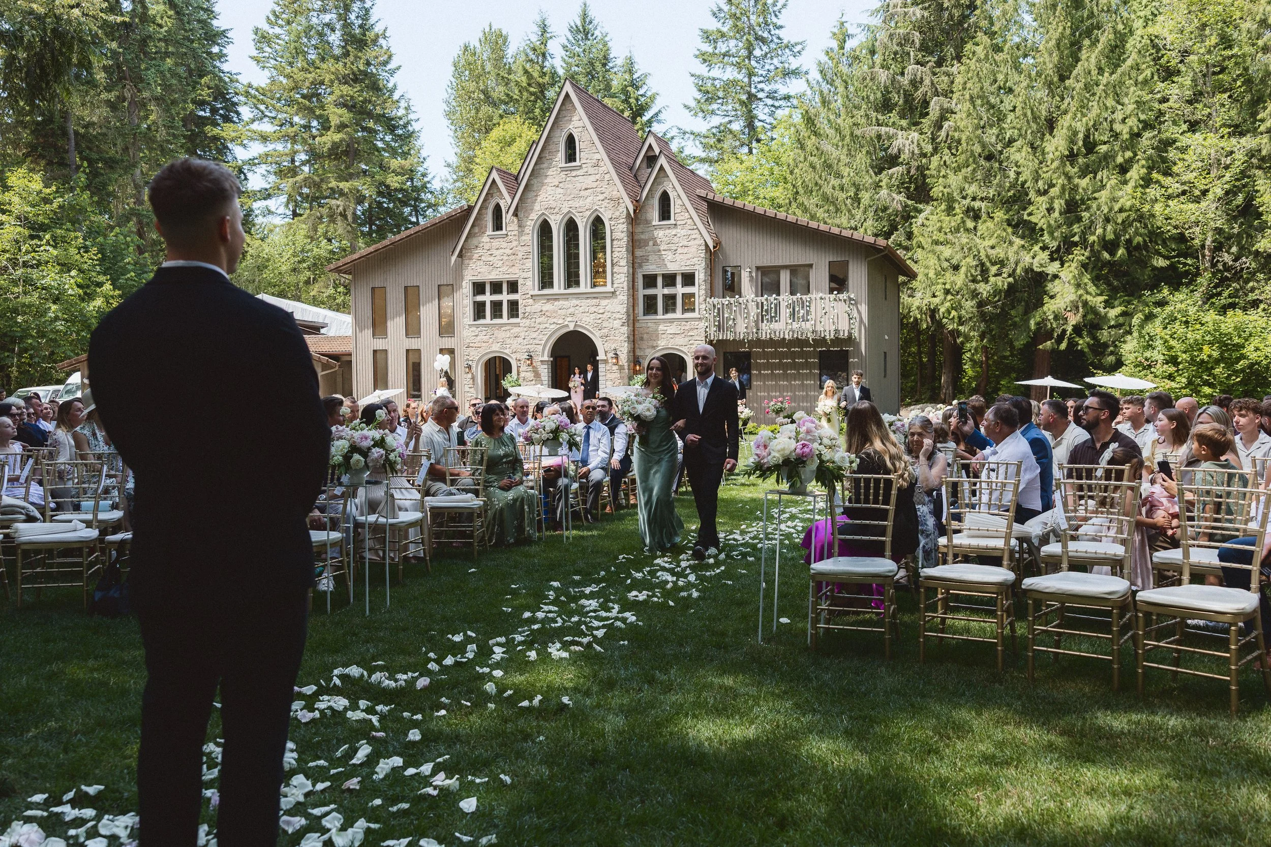 Wide view of the ceremony setup and guests taking their seats outdoors.