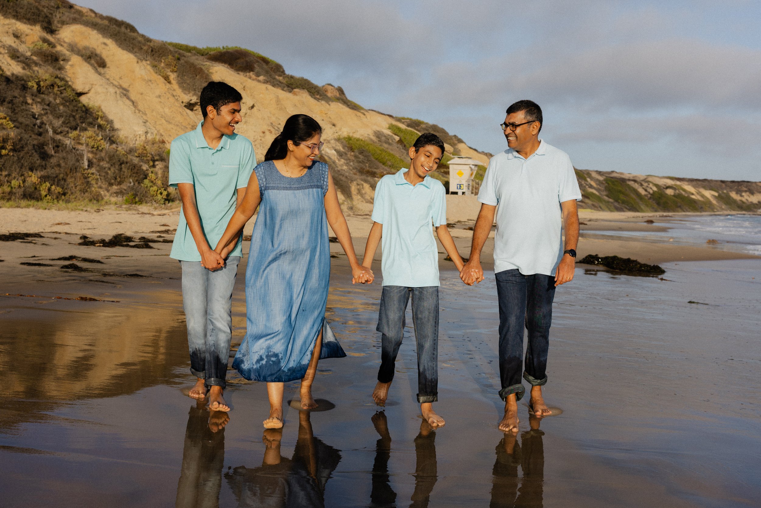 Family walking barefoot on the sand during family photos at Crystal Cove in Newport Beach.