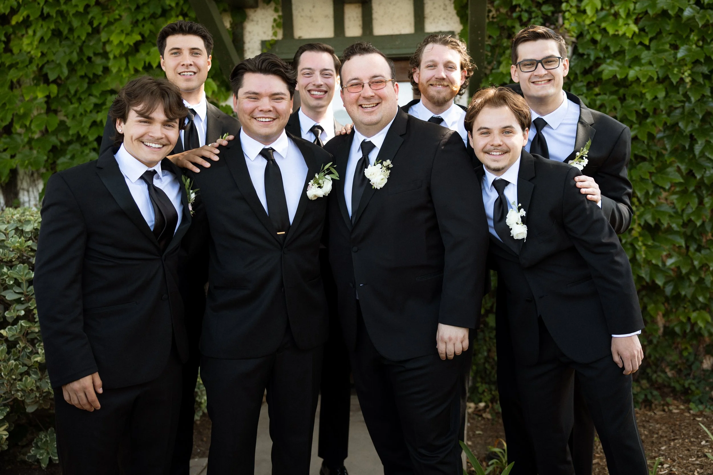 Groom and his groomsmen smile arm in arm for a group portrait