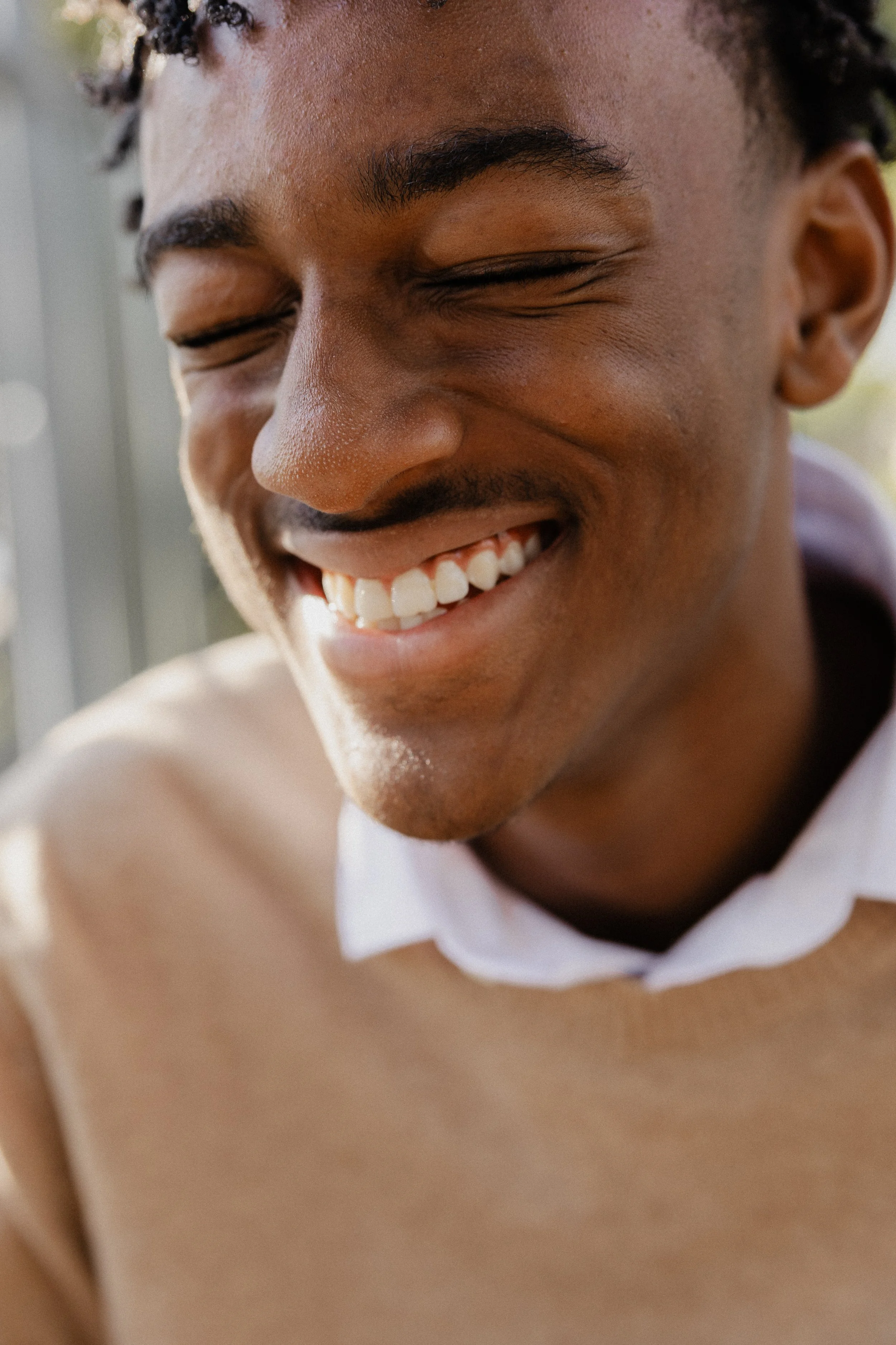 Extreme close-up of a teenage boy laughing with eyes closed, capturing a candid moment during an Irvine photography session.