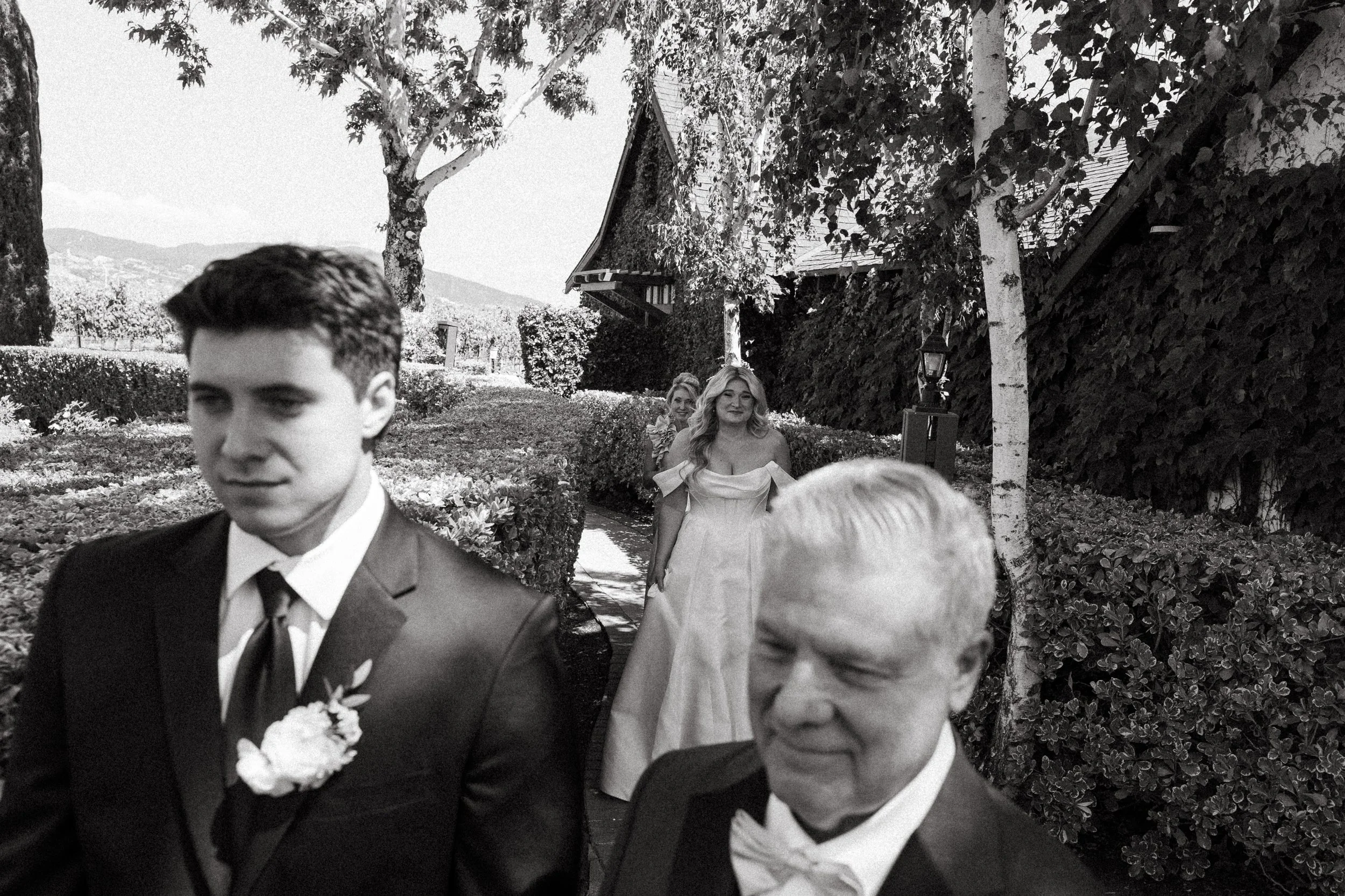 Bride approaches her father from behind for a first look in black and white
