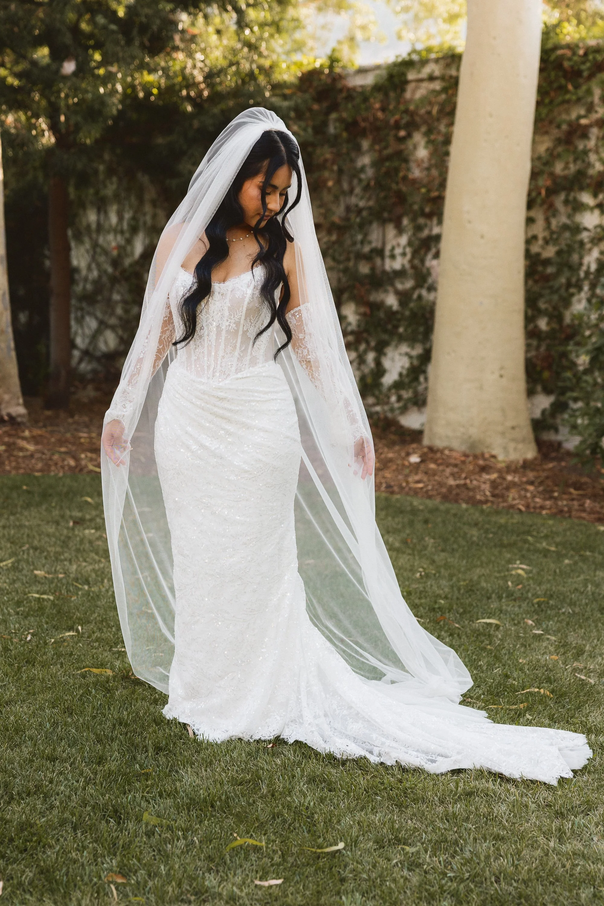 Bride looking down with full lace veil draped around her at Los Angeles River Center and Gardens.
