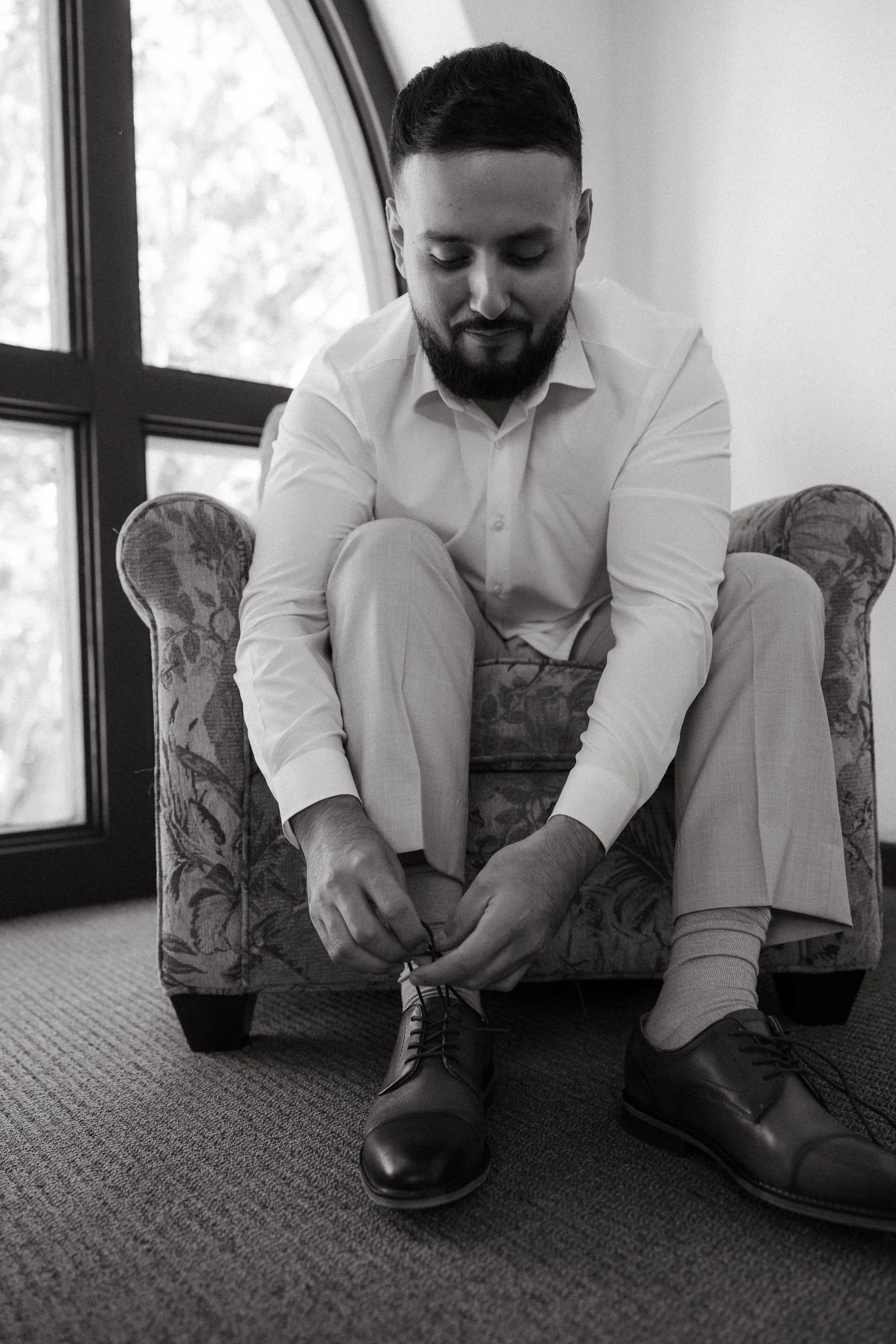 Groom tying shoes before wedding ceremony at Los Angeles River Center