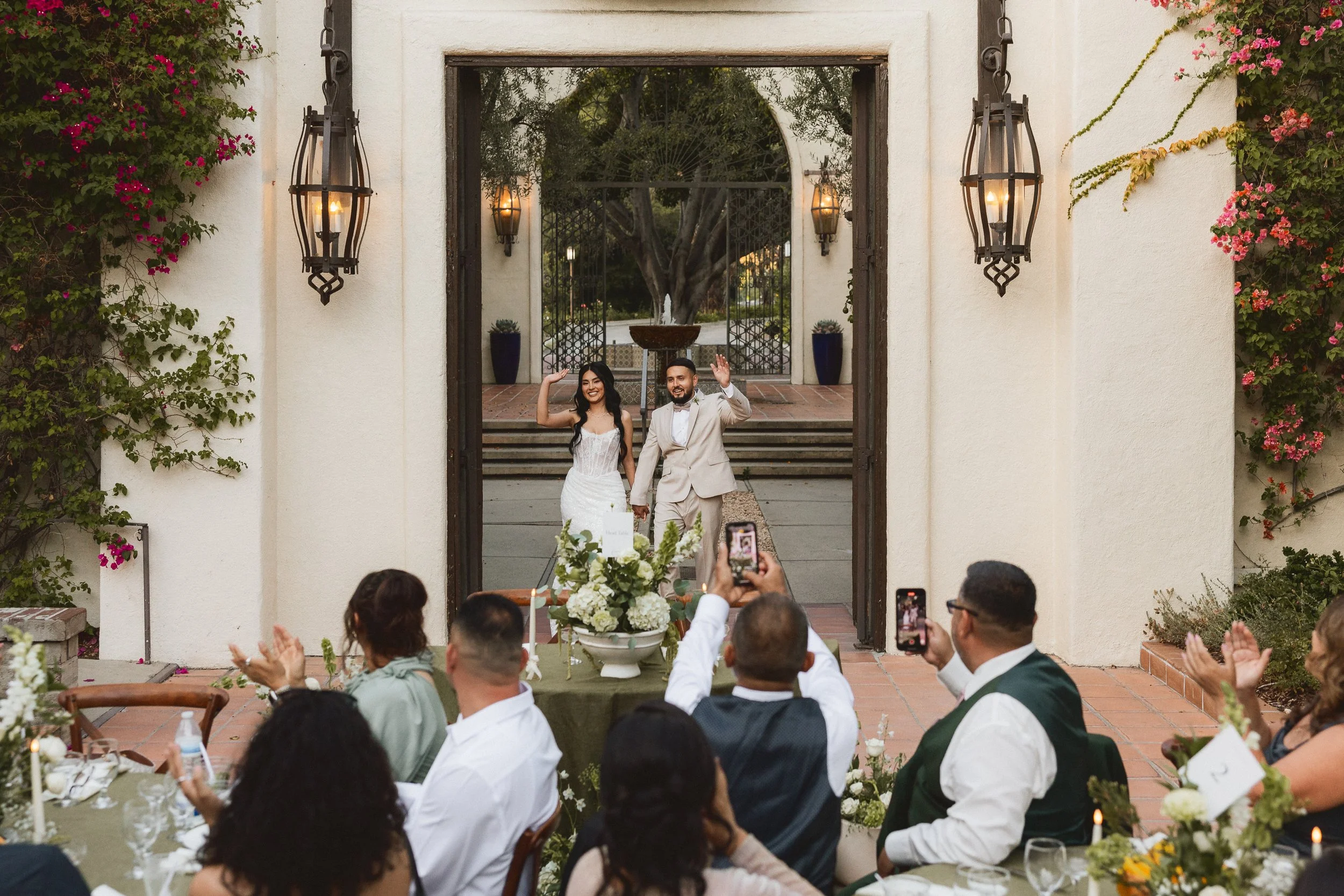 Bride and groom waving as they make their grand entrance into the reception courtyard