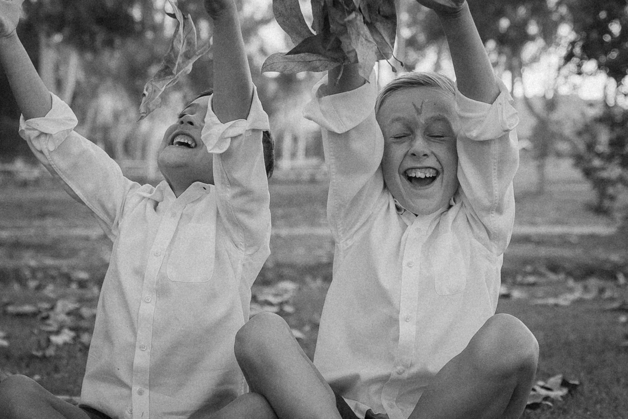 Two brothers throwing leaves and laughing during family photos at Turtle Rock Community Park in Irvine, CA