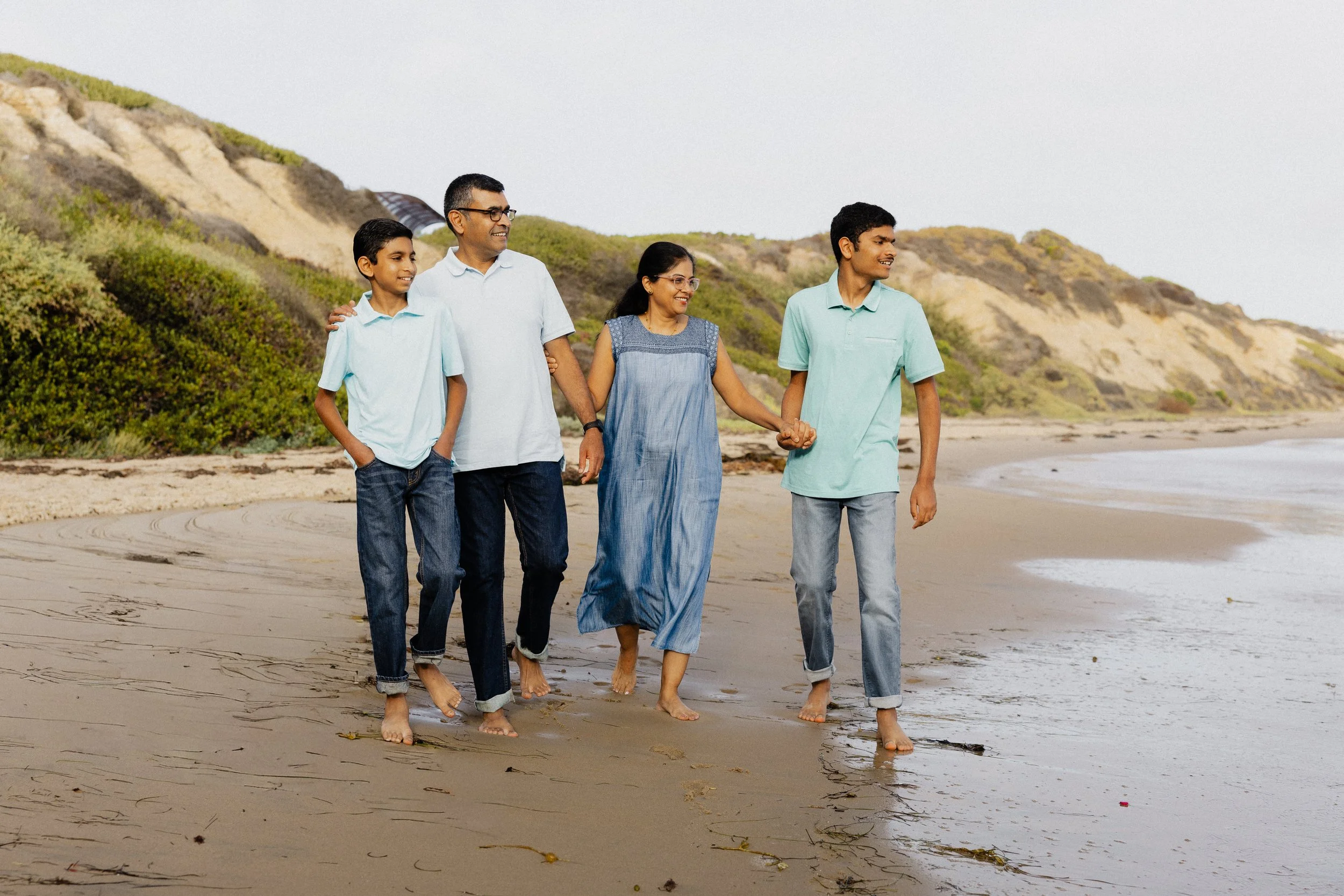 Family walking barefoot along the shoreline at Crystal Cove State Park in Newport Beach.